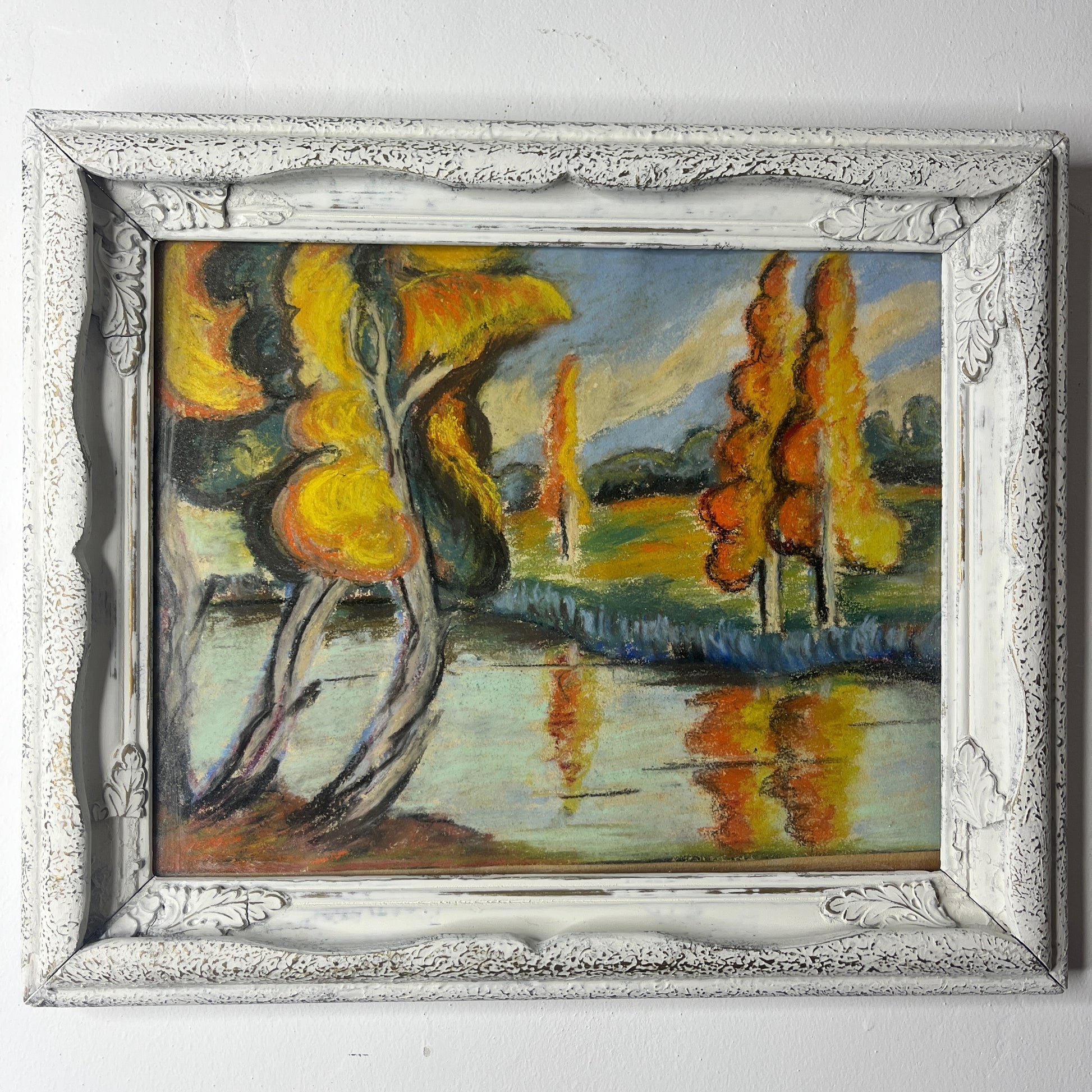 Painting of a landscape with trees and water in a decorative frame.