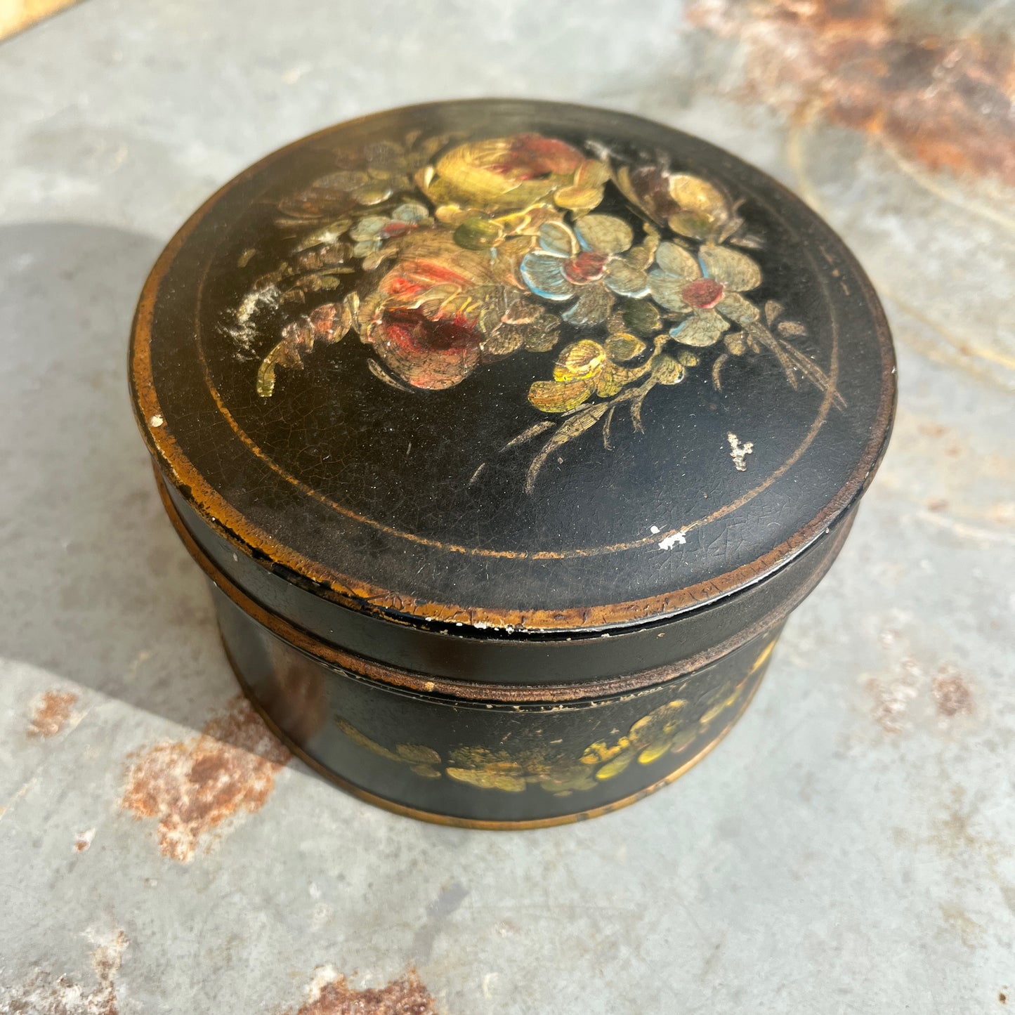 Round black decorative box with floral design on a textured surface