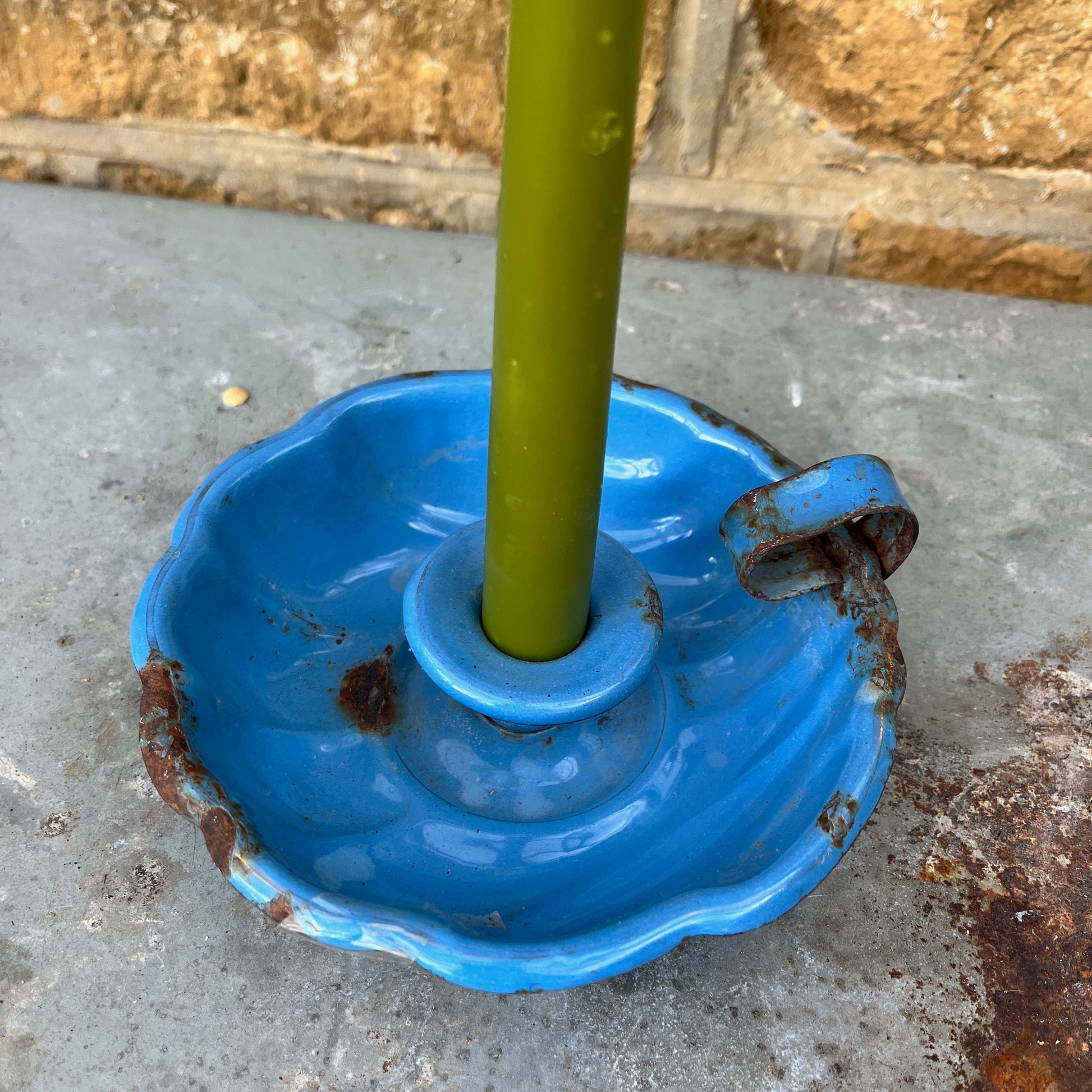 A blue enamel French candle holder with a glossy, vibrant finish, featuring a shallow, round dish to hold a tapered candle. The holder has a smooth, slightly scalloped edge, exuding classic French charm