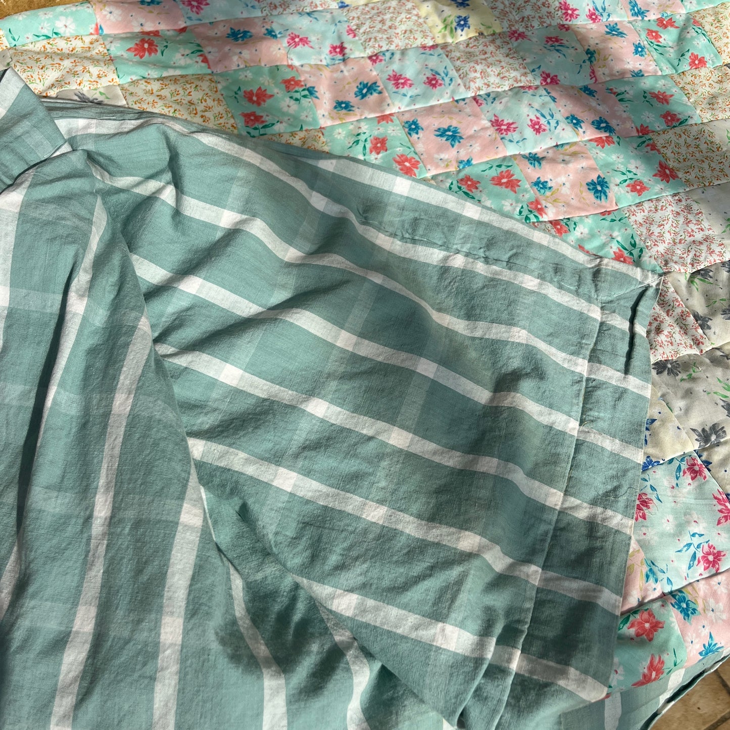 Green and white striped patchwork quilt with floral-patterned fabric in the background