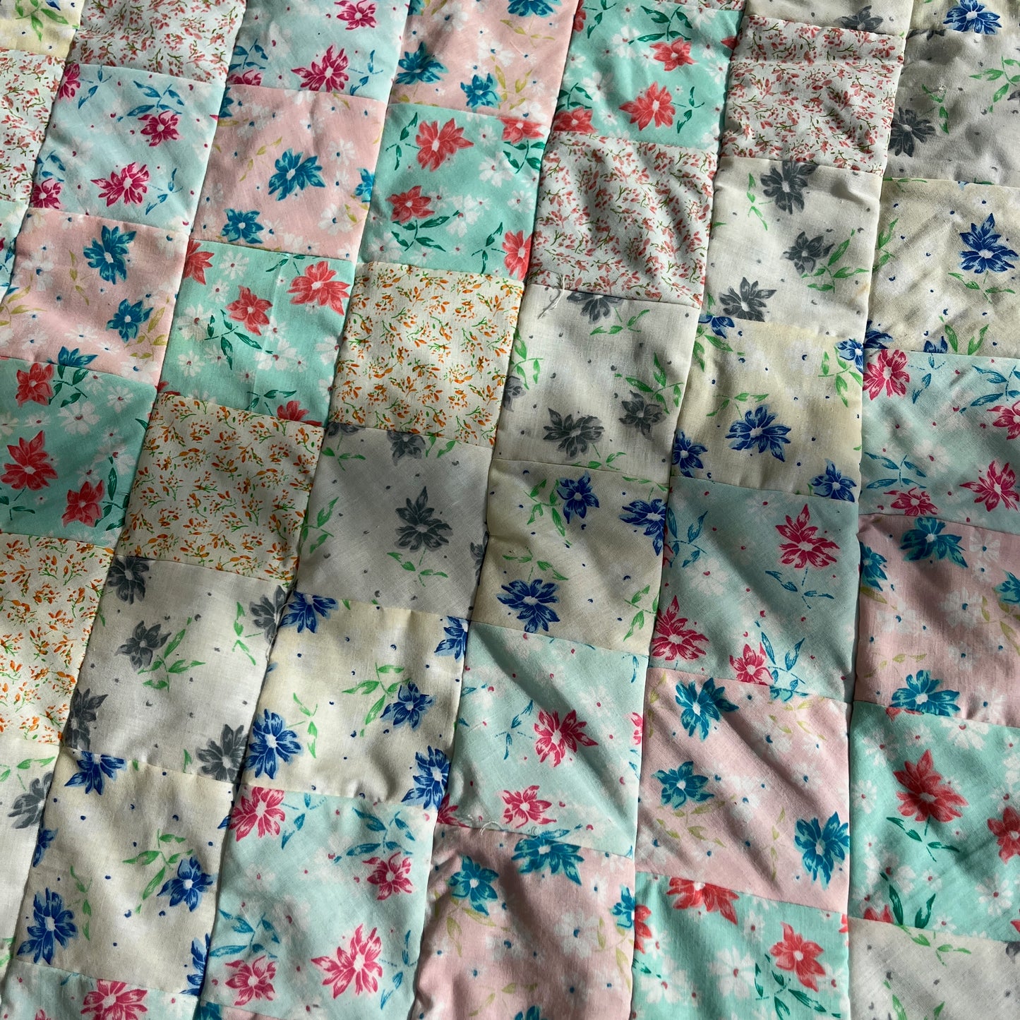 Green and white striped patchwork quilt with floral-patterned fabric in the background