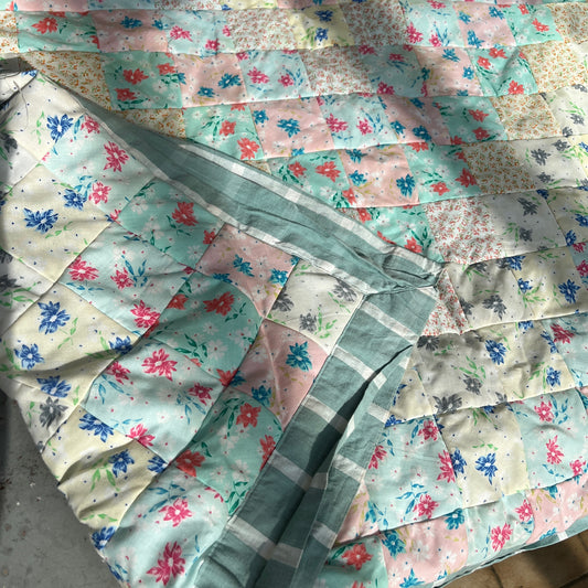 Green and white striped patchwork quilt with floral-patterned fabric in the background