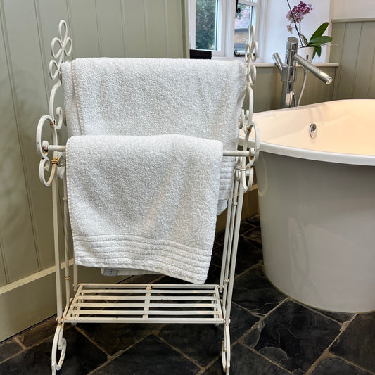 A French-style decorative towel rail crafted from iron with a white finish. The rail features ornate scrollwork and delicate curves, exuding vintage elegance and rustic charm