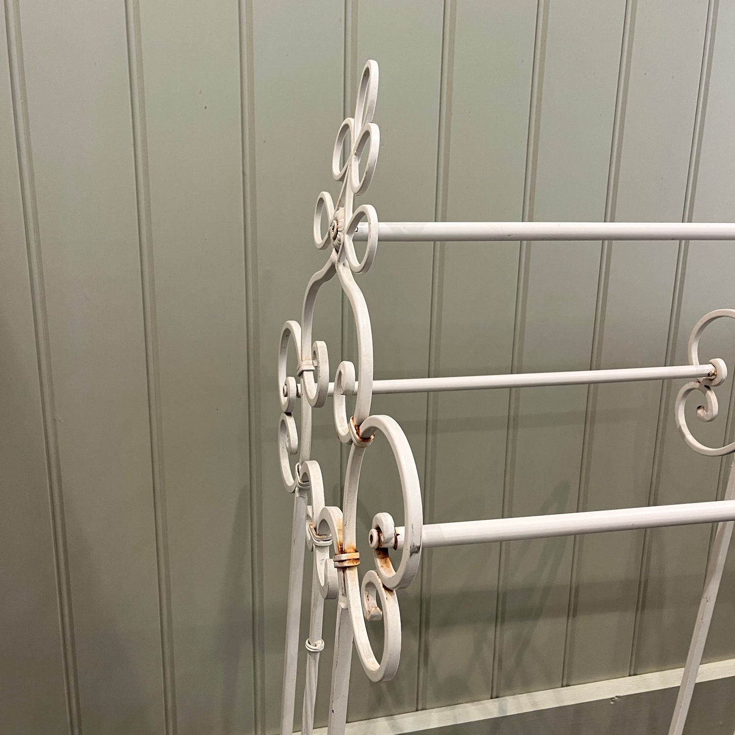 A French-style decorative towel rail crafted from iron with a white finish. The rail features ornate scrollwork and delicate curves, exuding vintage elegance and rustic charm