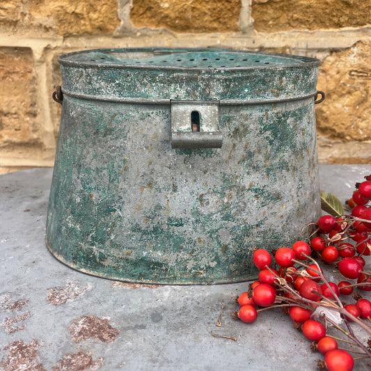 Rustic metal container with red berries on a stone surface