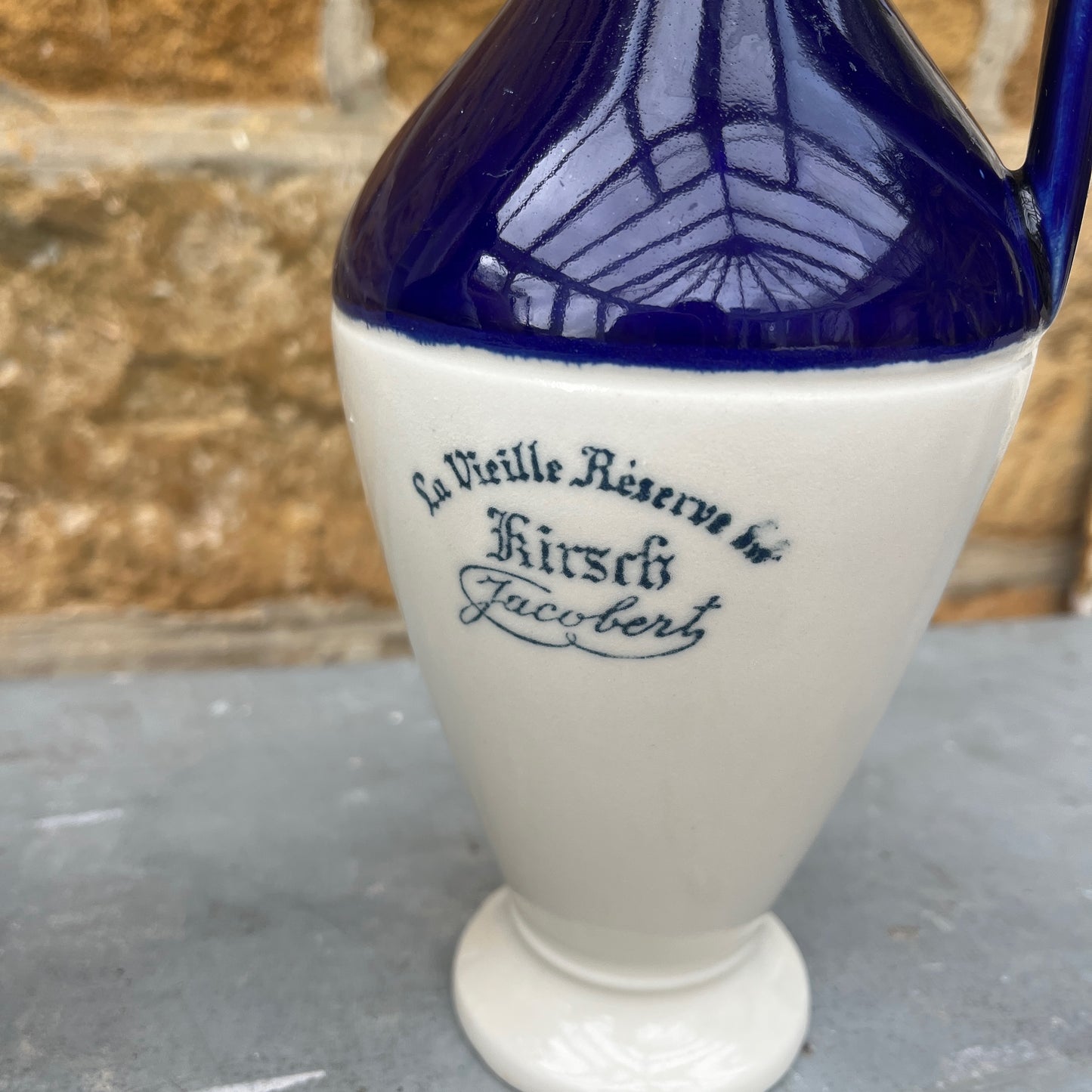 Blue & white ceramic container with text on a gray surface.