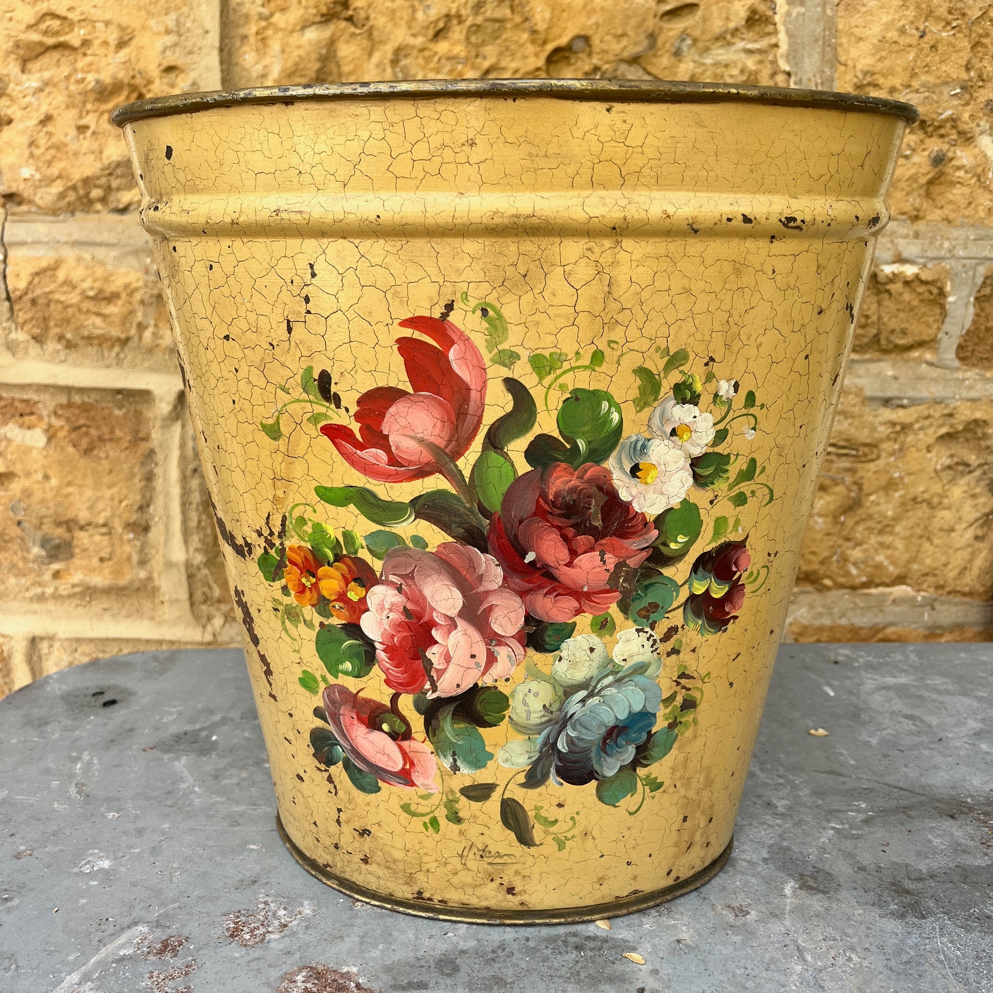 A pair of French tole peinte waste bins, hand-painted with intricate floral designs in soft pastels on a green or mustard background.