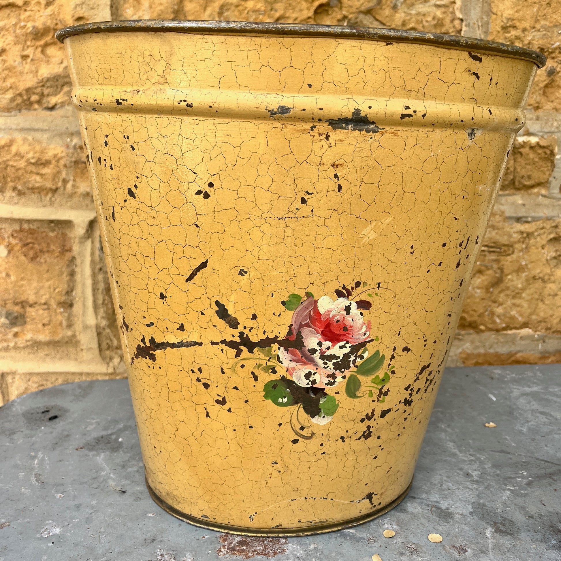 A pair of French tole peinte waste bins, hand-painted with intricate floral designs in soft pastels on a green or mustard background.