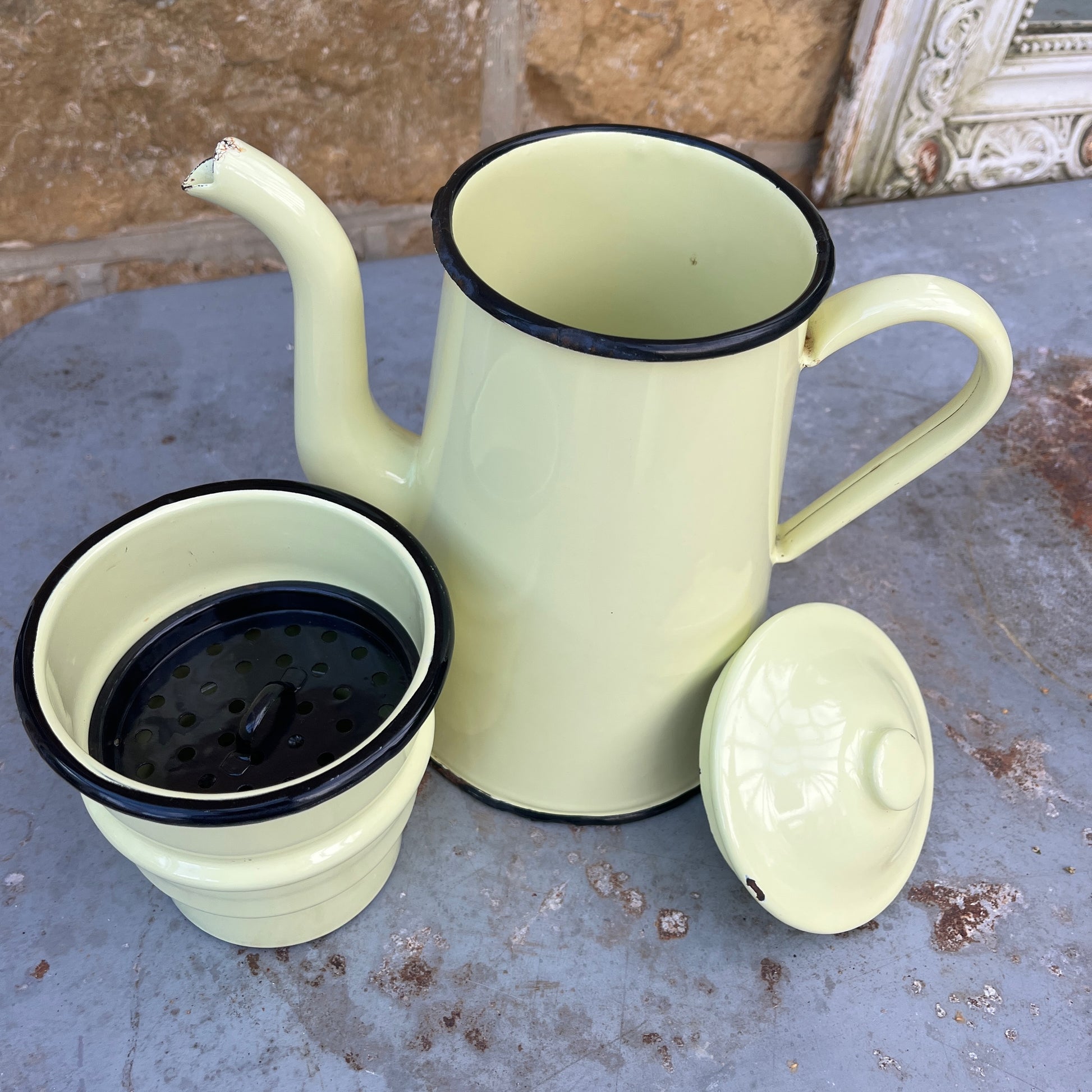 A vintage French yellow enamel coffee pot, circa 1920s, with a soft yellow body and black trim. It includes all four brewing pieces, showing minor chips and rust that add to its authentic patina