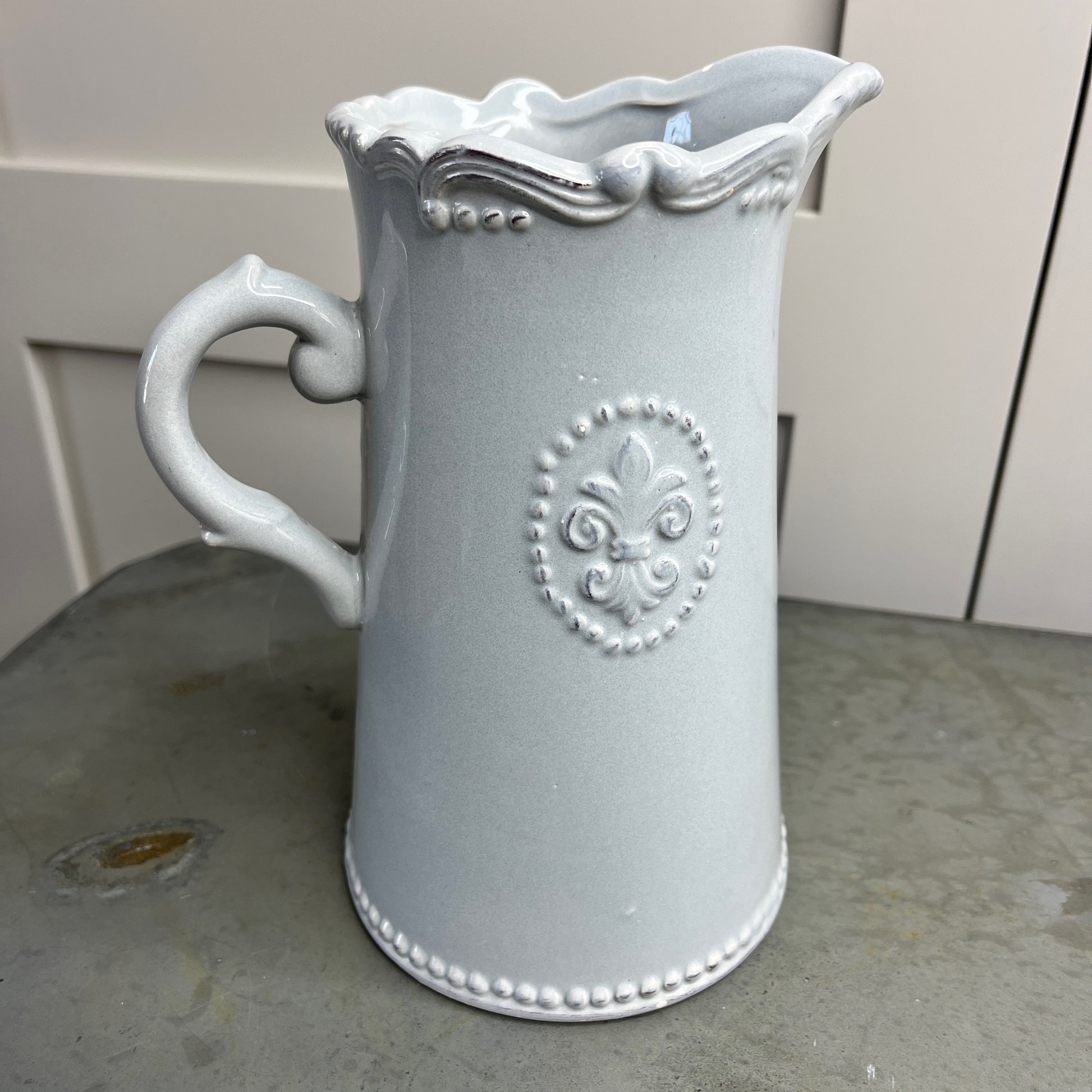 Decorative gray pitcher with intricate designs on a surface.