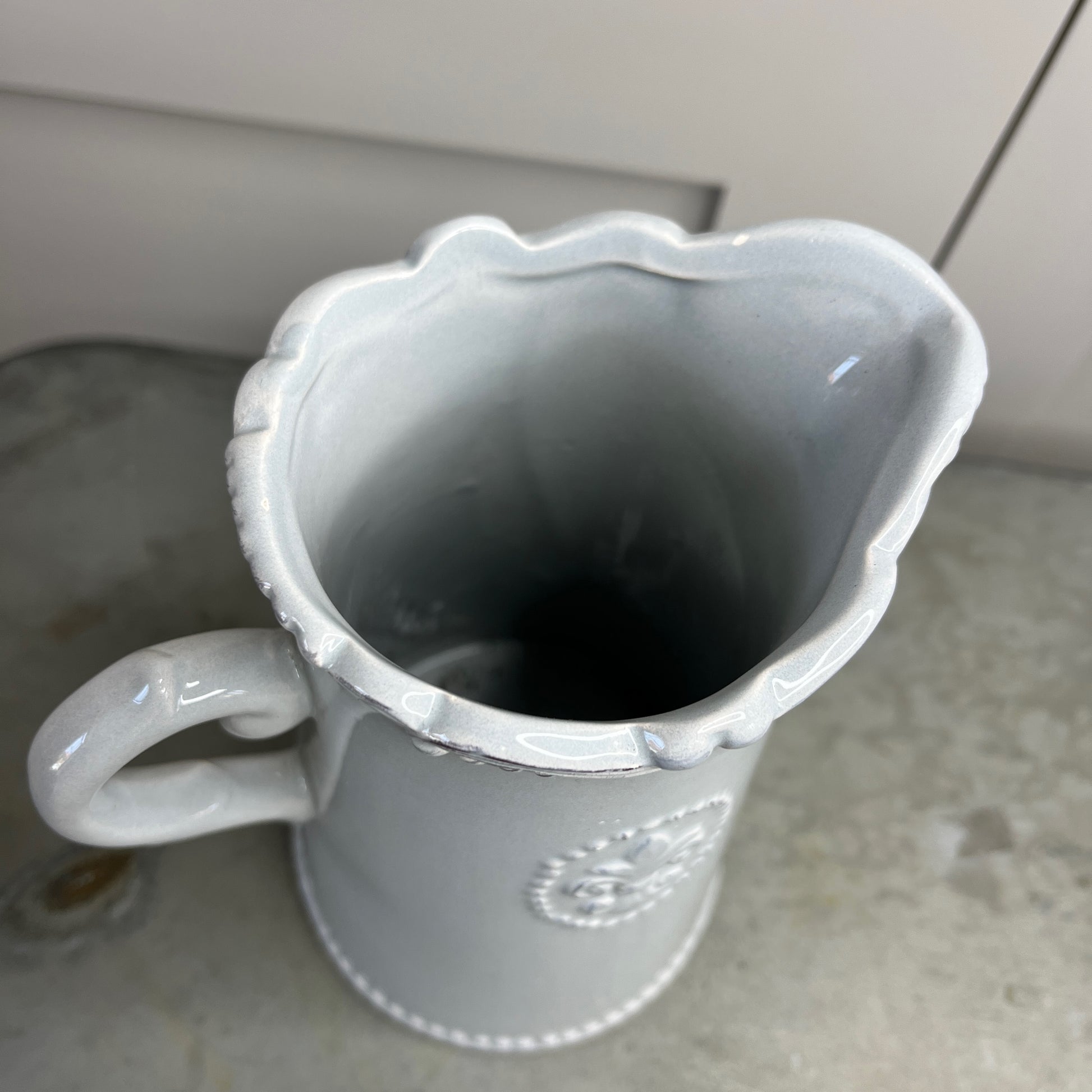 White ceramic pitcher on a countertop with a blurred background