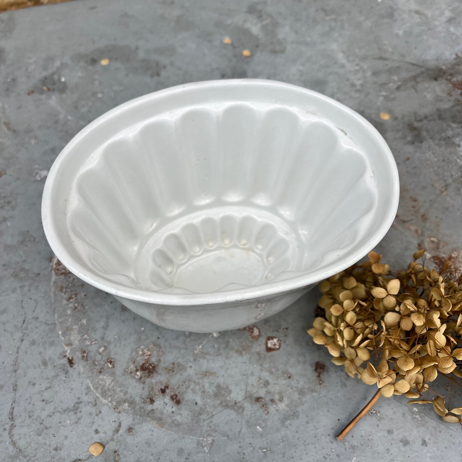 A vintage ceramic white jelly mould with a smooth, glossy finish, featuring a classic fluted design and an oval shape