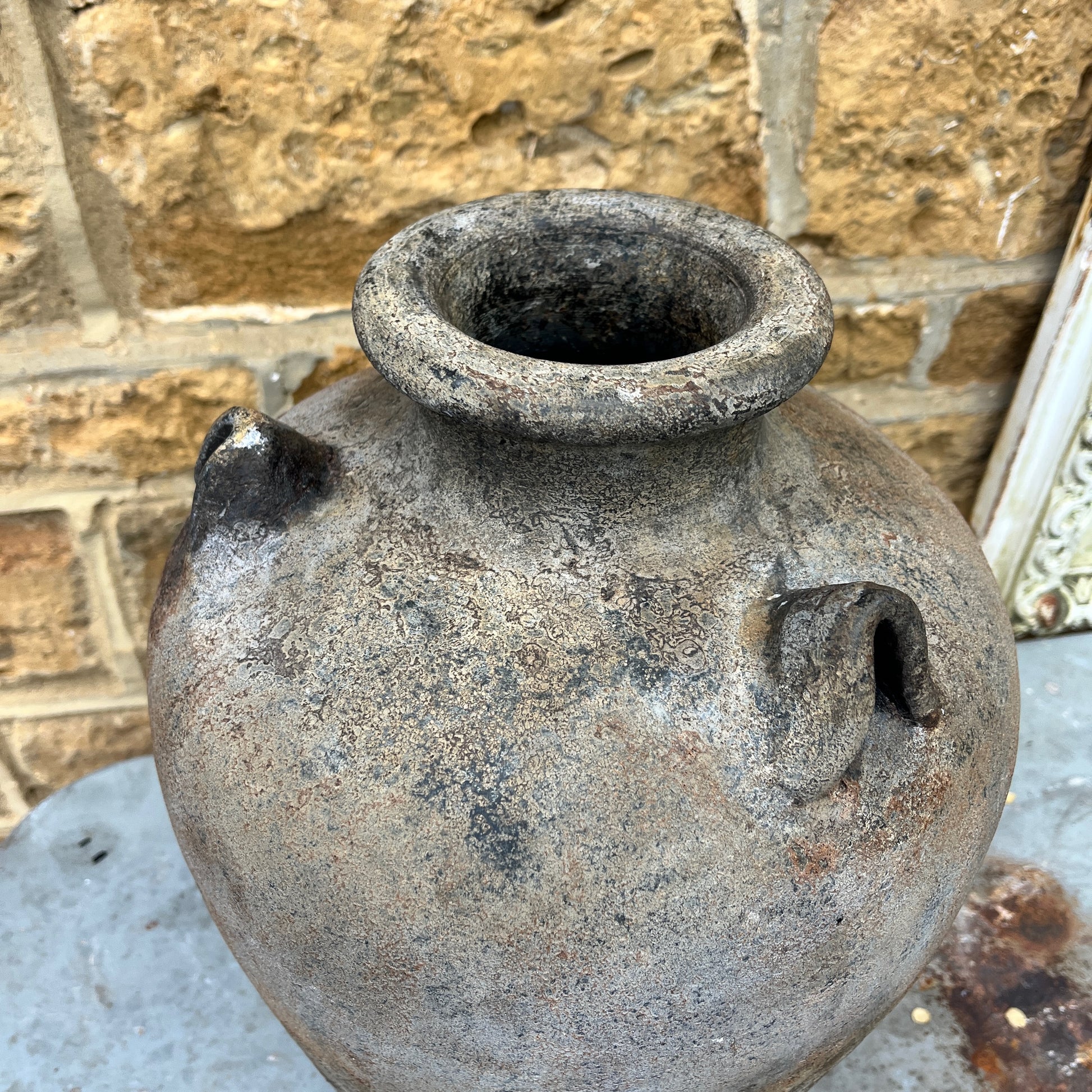 A large ceramic pot with a textured brown & black finish, featuring three evenly spaced handles around its wide, rounded body. The pot has a rough, slightly textured surface, exuding modern elegance