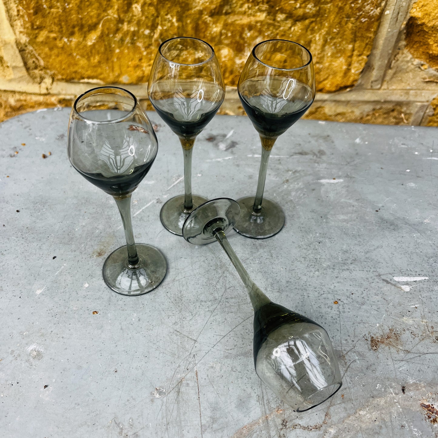 Set of four 1970s smokey grey liqueur glasses with slender stems and gently flared bowls. The glasses feature a vintage mid-century modern design with a subtle tinted finish.