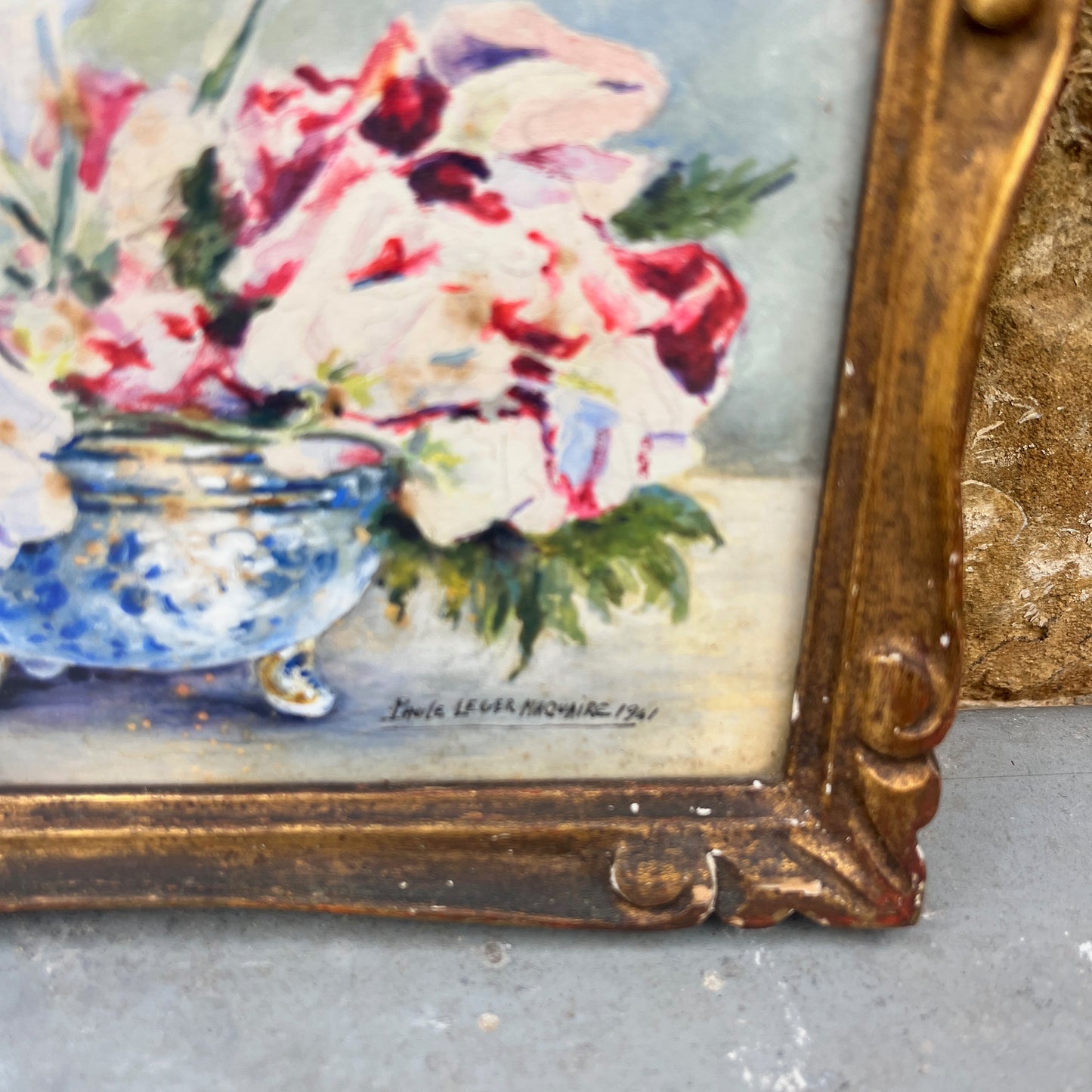 Floral painting in a decorative gold frame on a textured surface