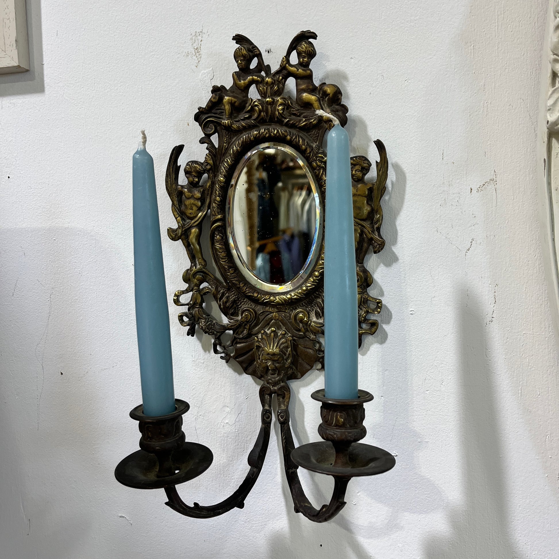 Elegant pair of antique French cenelle sconces featuring intricate scrollwork and a weathered patina and bevelled oval mirror, reflecting classic 19th-century craftsmanship.