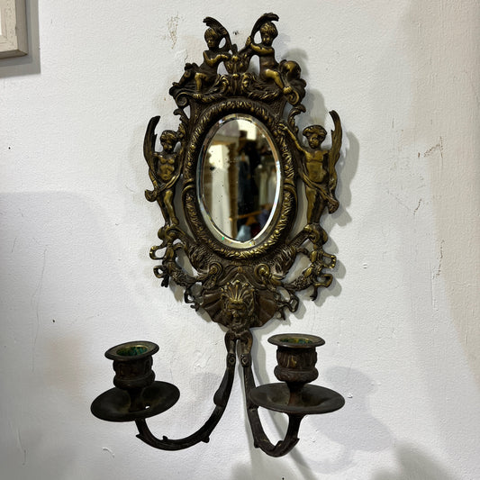 Elegant pair of antique French cenelle sconces featuring intricate scrollwork and a weathered patina and bevelled oval mirror, reflecting classic 19th-century craftsmanship.