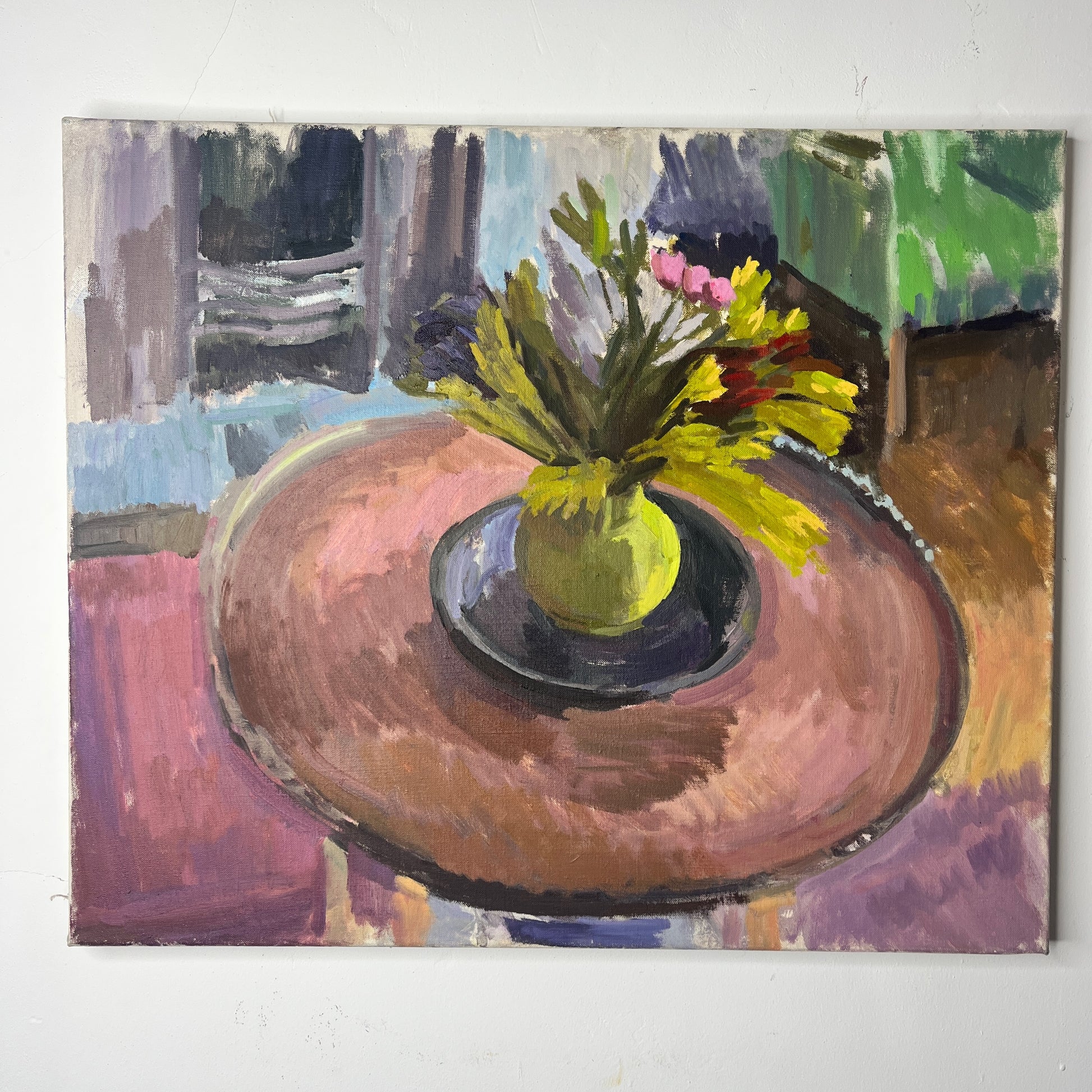 An oil-on-canvas still life painting capturing a serene living room scene, featuring a bouquet of pink tulips gracefully arranged in a green vase on a wooden table. In the room is a green armchair, and fire place, evoking a sense of quiet elegance. and coziness.