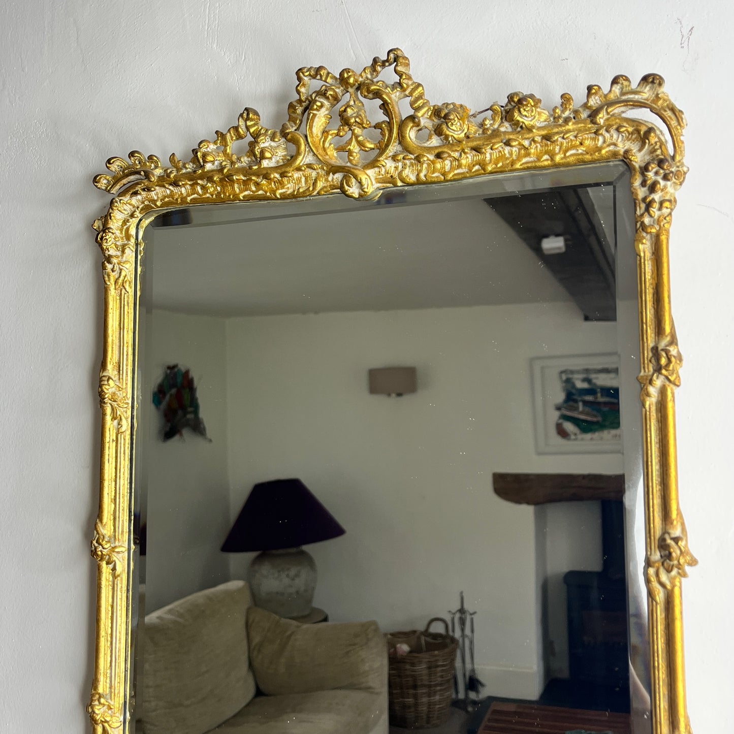 A vintage Rococo-style gilded beveled mirror with an ornate, intricately carved frame featuring scrolling foliage, shells, and asymmetrical rocaille motifs, finished in a rich gold leaf patina.