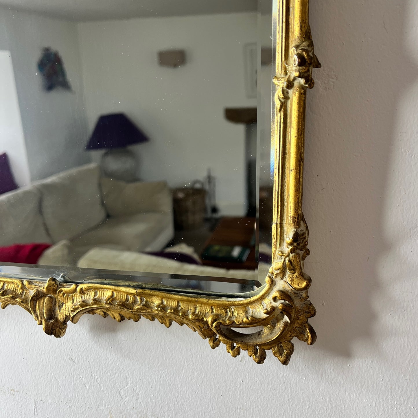 A vintage Rococo-style gilded beveled mirror with an ornate, intricately carved frame featuring scrolling foliage, shells, and asymmetrical rocaille motifs, finished in a rich gold leaf patina.