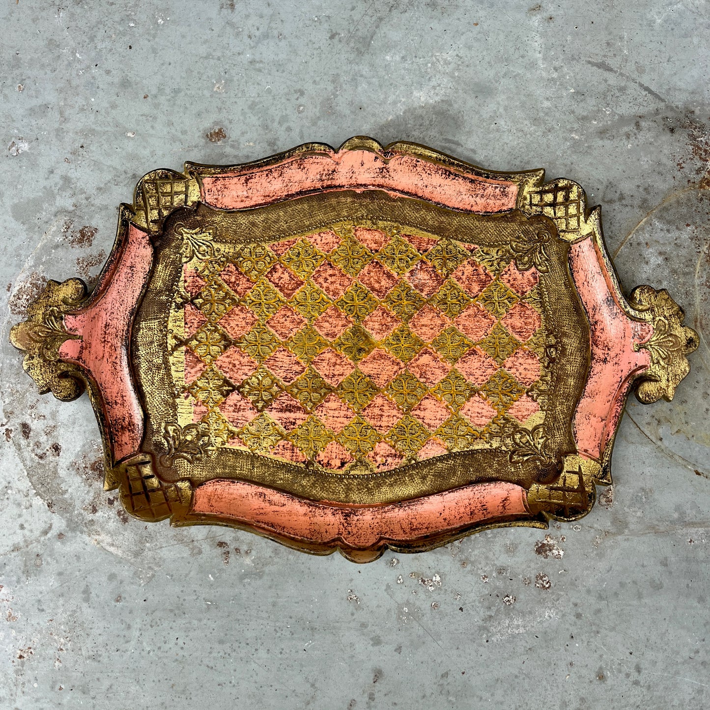 Decorative pink and gold florentine tray with a checkered pattern on a textured gray background