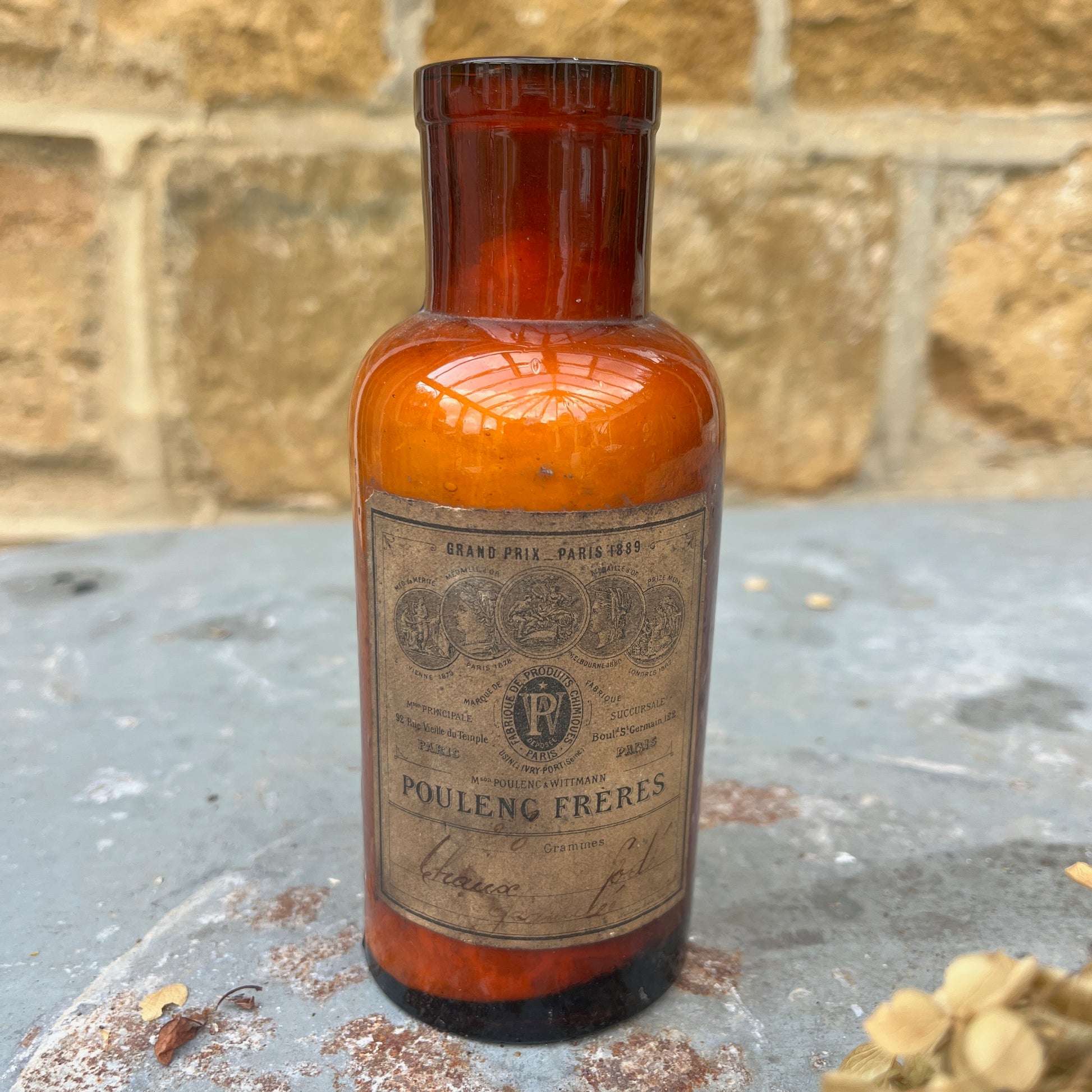 A pair of antique spice or medicine jars made of brown glass, each featuring etched labels and cork stoppers, filled with contents such as dried herbs and powders. The jars have a vintage, apothecary-style design.