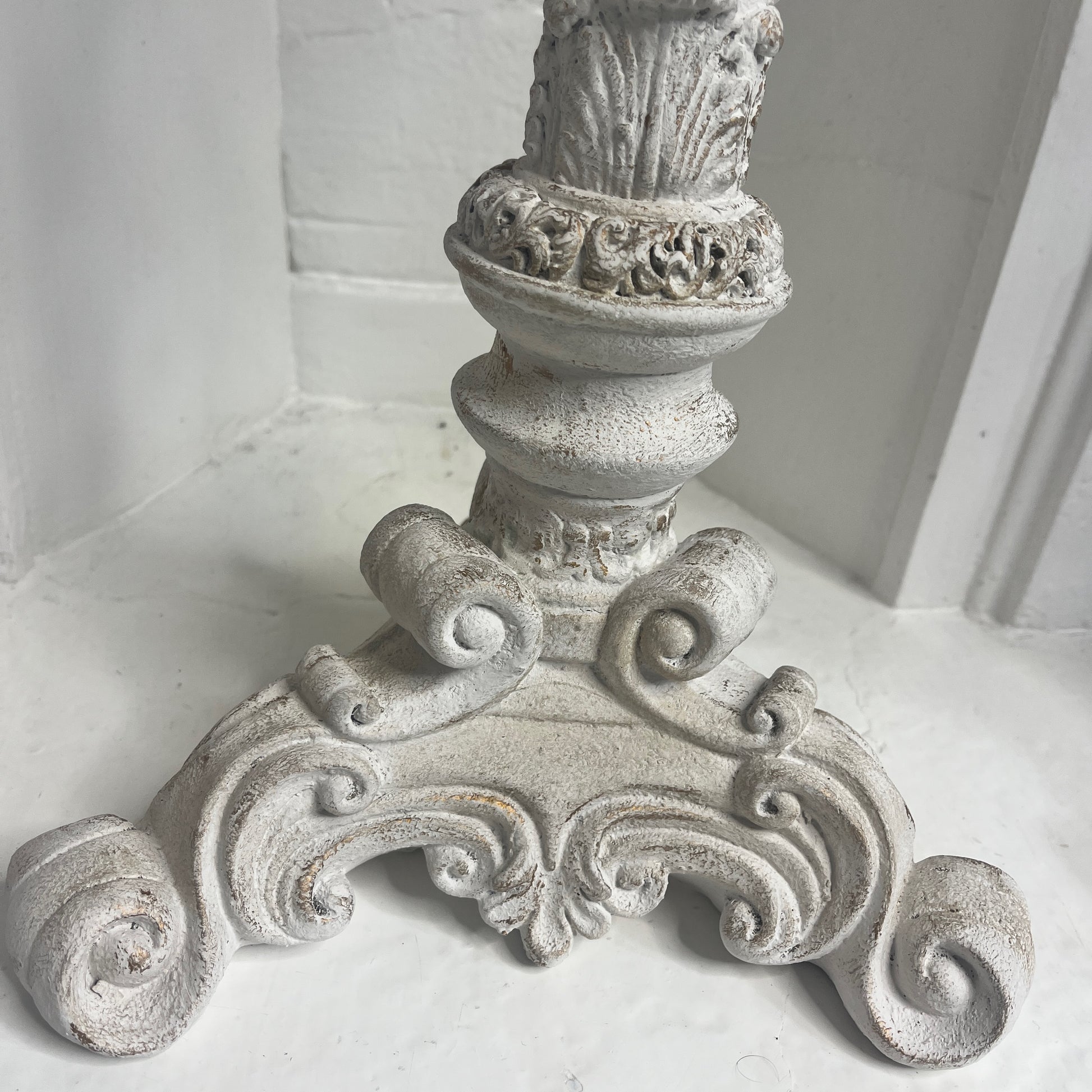 A pair of tall French-style candle holders crafted from wood, painted white, featuring elegant, carved detailing and a slightly distressed finish. Each holder supports a single candle, exuding classic rustic charm