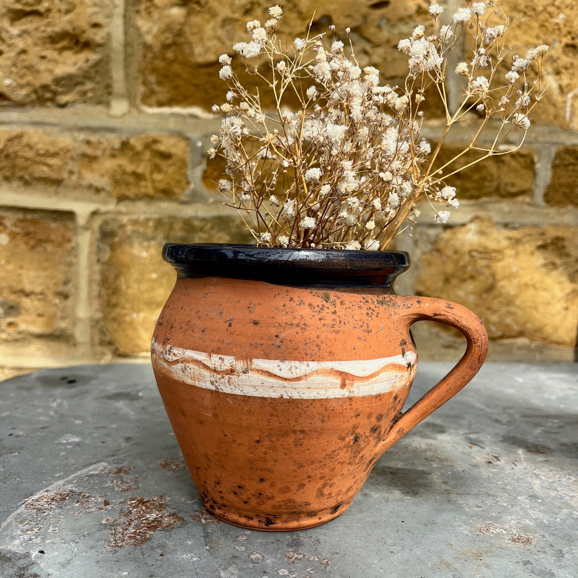 Rustic terracotta jug with a white painted band encircling the center, showcasing traditional craftsmanship.