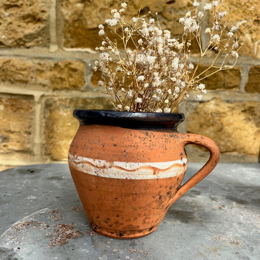 Rustic terracotta jug with a white painted band encircling the center, showcasing traditional craftsmanship.
