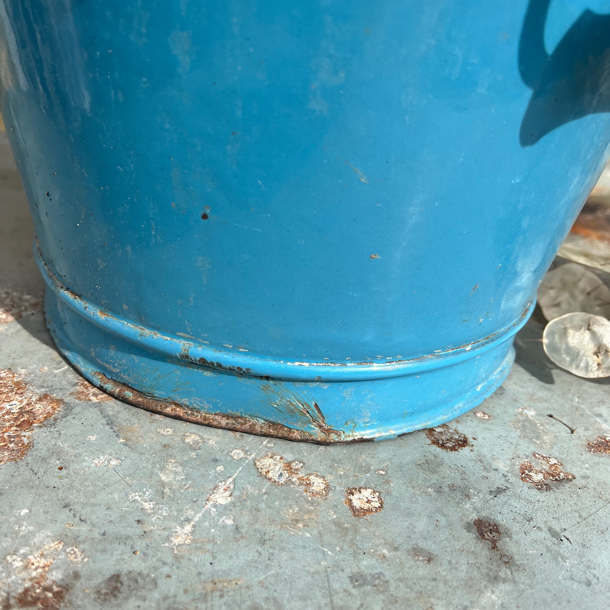 Vintage-style blue metal bucket with white enamel interior and wooden grip handle, placed on a rustic surface