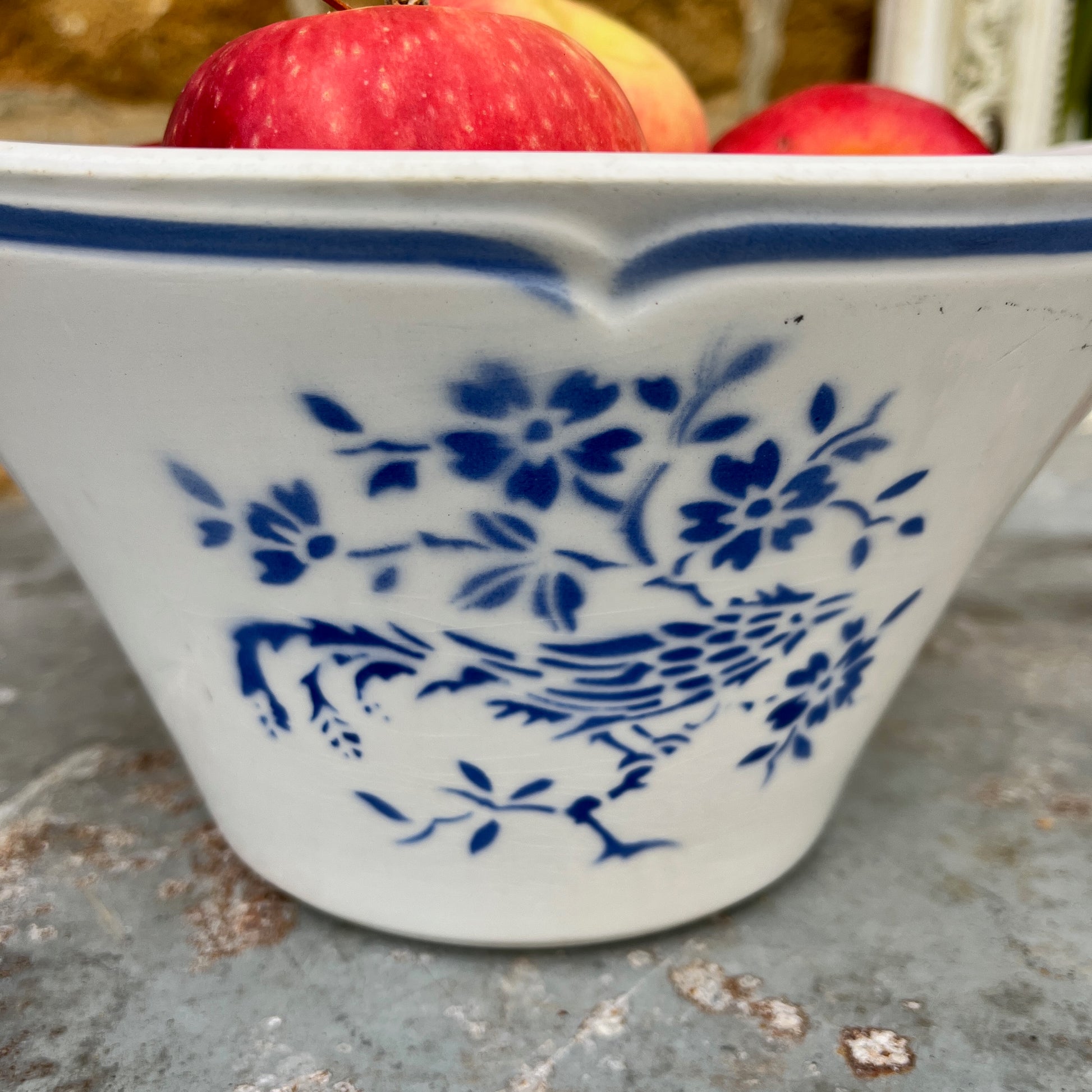 A vintage French blue and white ceramic bowl, likely from the late 19th to early 20th century, featuring a scalloped, blue line around the rim. The bowl is adorned with a delicate floral pattern in cobalt blue against a creamy white background, showcasing classic French country charm with minor age-related wear