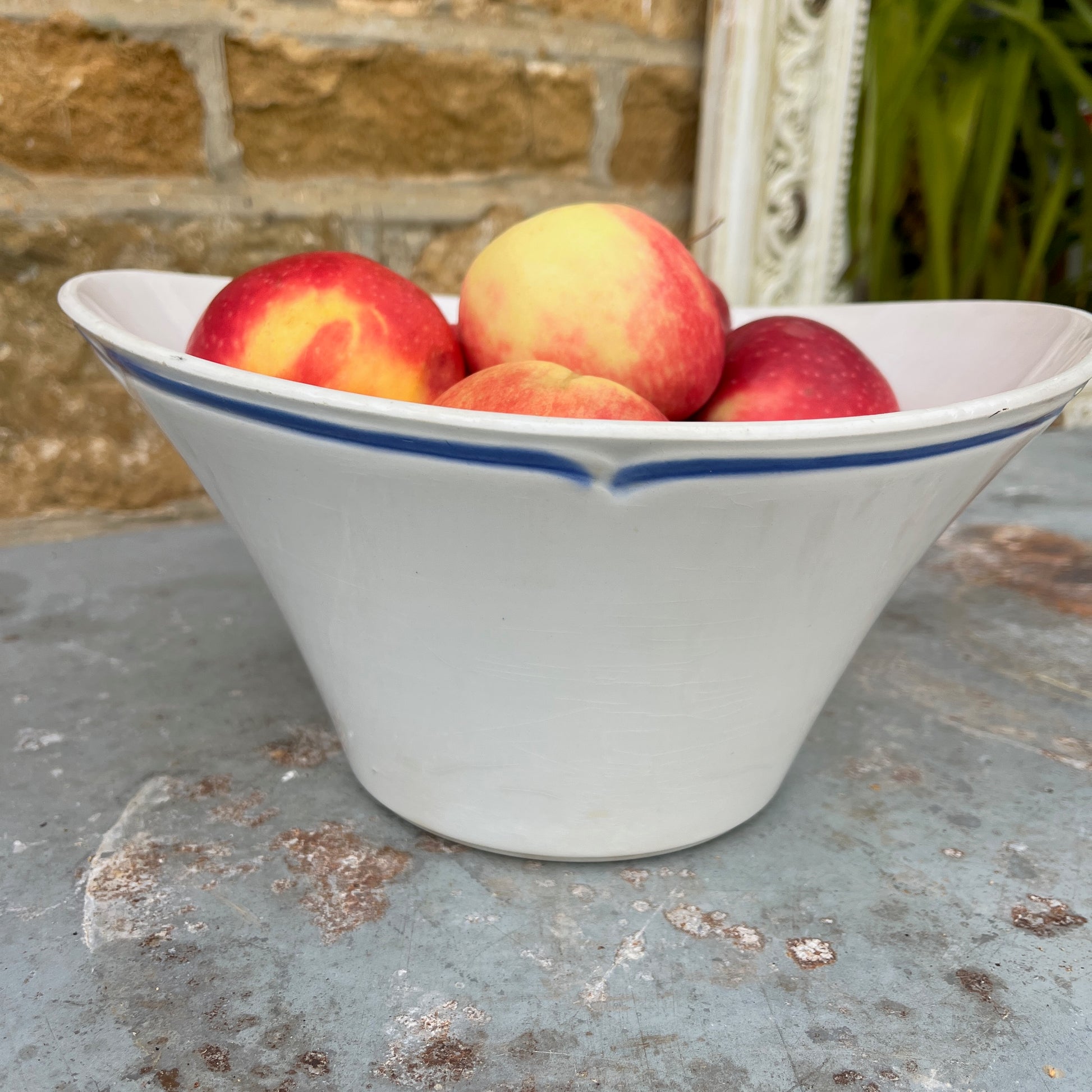 A vintage French blue and white ceramic bowl, likely from the late 19th to early 20th century, featuring a scalloped, blue line around the rim. The bowl is adorned with a delicate floral pattern in cobalt blue against a creamy white background, showcasing classic French country charm with minor age-related wear
