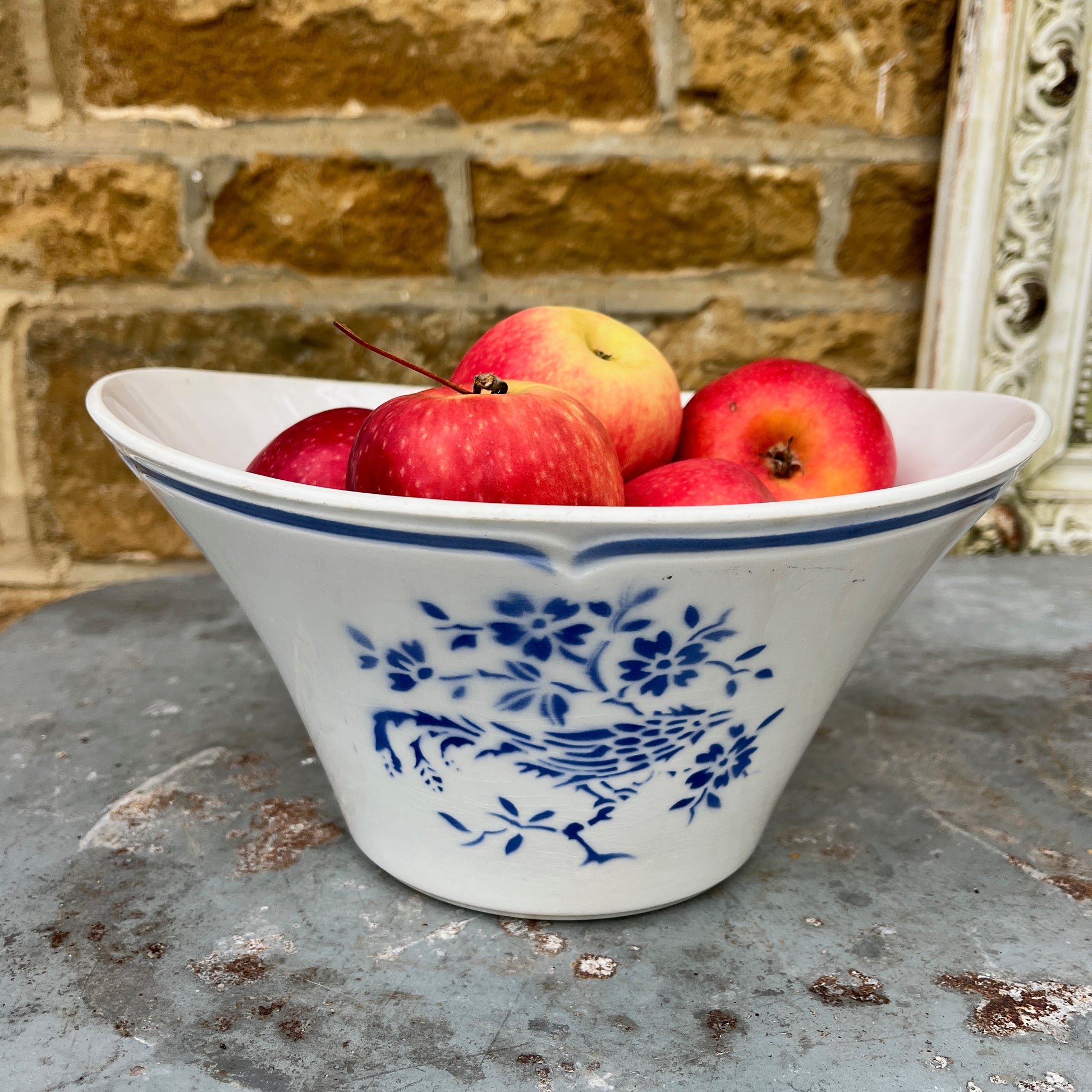 A vintage French blue and white ceramic bowl, likely from the late 19th to early 20th century, featuring a scalloped, blue line around the rim. The bowl is adorned with a delicate floral pattern in cobalt blue against a creamy white background, showcasing classic French country charm with minor age-related wear