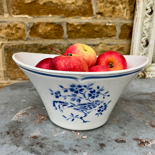 A vintage French blue and white ceramic bowl, likely from the late 19th to early 20th century, featuring a scalloped, blue line around the rim. The bowl is adorned with a delicate floral pattern in cobalt blue against a creamy white background, showcasing classic French country charm with minor age-related wear