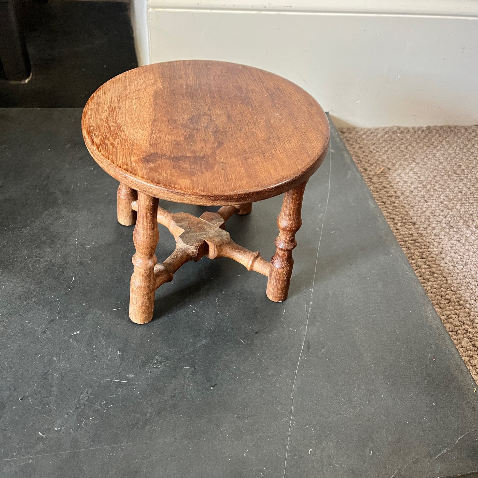 A collection of rustic wooden stools, each with a weathered finish in varying shades of brown, blue and yellow, featuring simple, sturdy designs with four legs