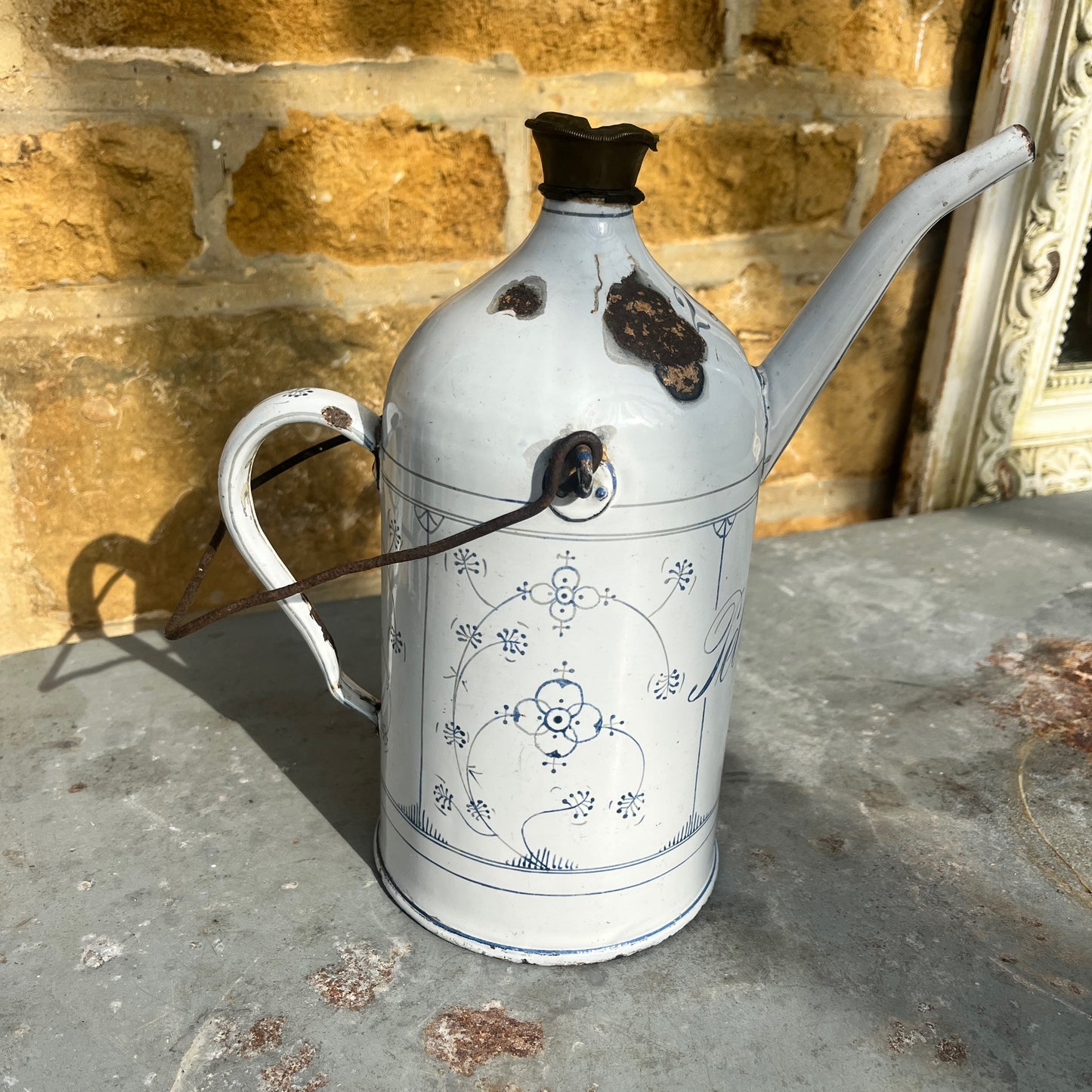 A vintage French enamel petroleum canister with a glossy finish, featuring elegant blue and white detailing in a classic pattern.