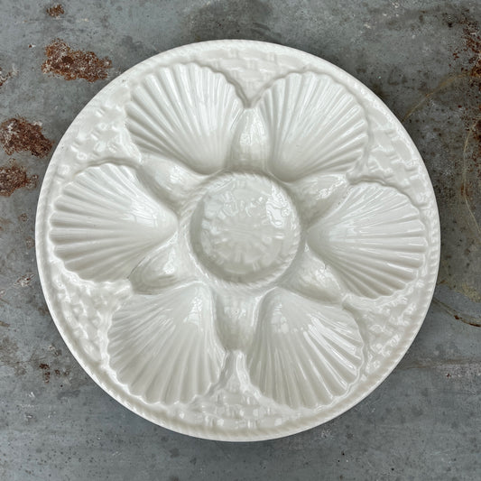 Vintage white ceramic oyster plate with shell design on a textured surface - French