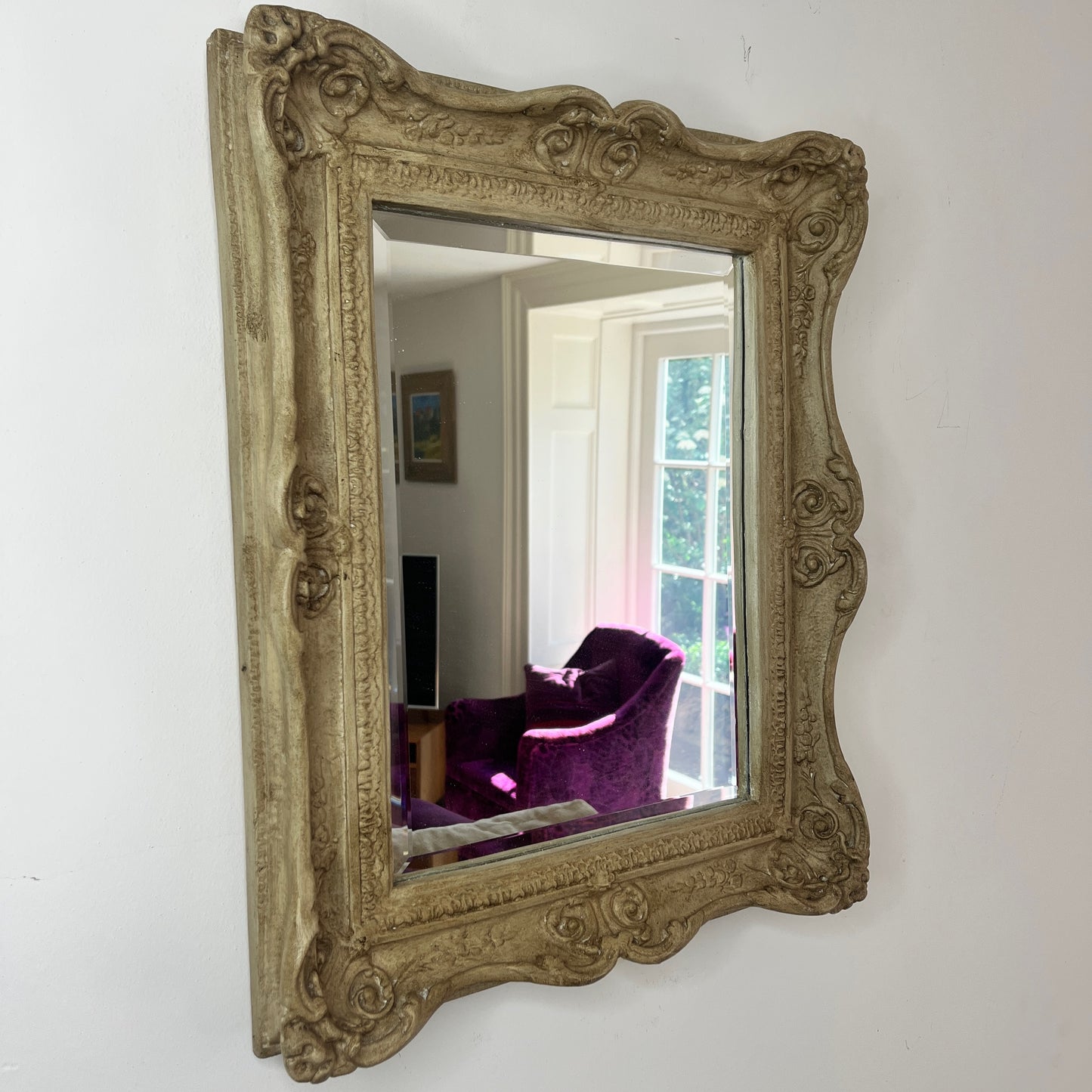 A vintage beveled rectangular mirror with a polished glass surface, framed by a weathered wooden decorative border in a warm, aged finish