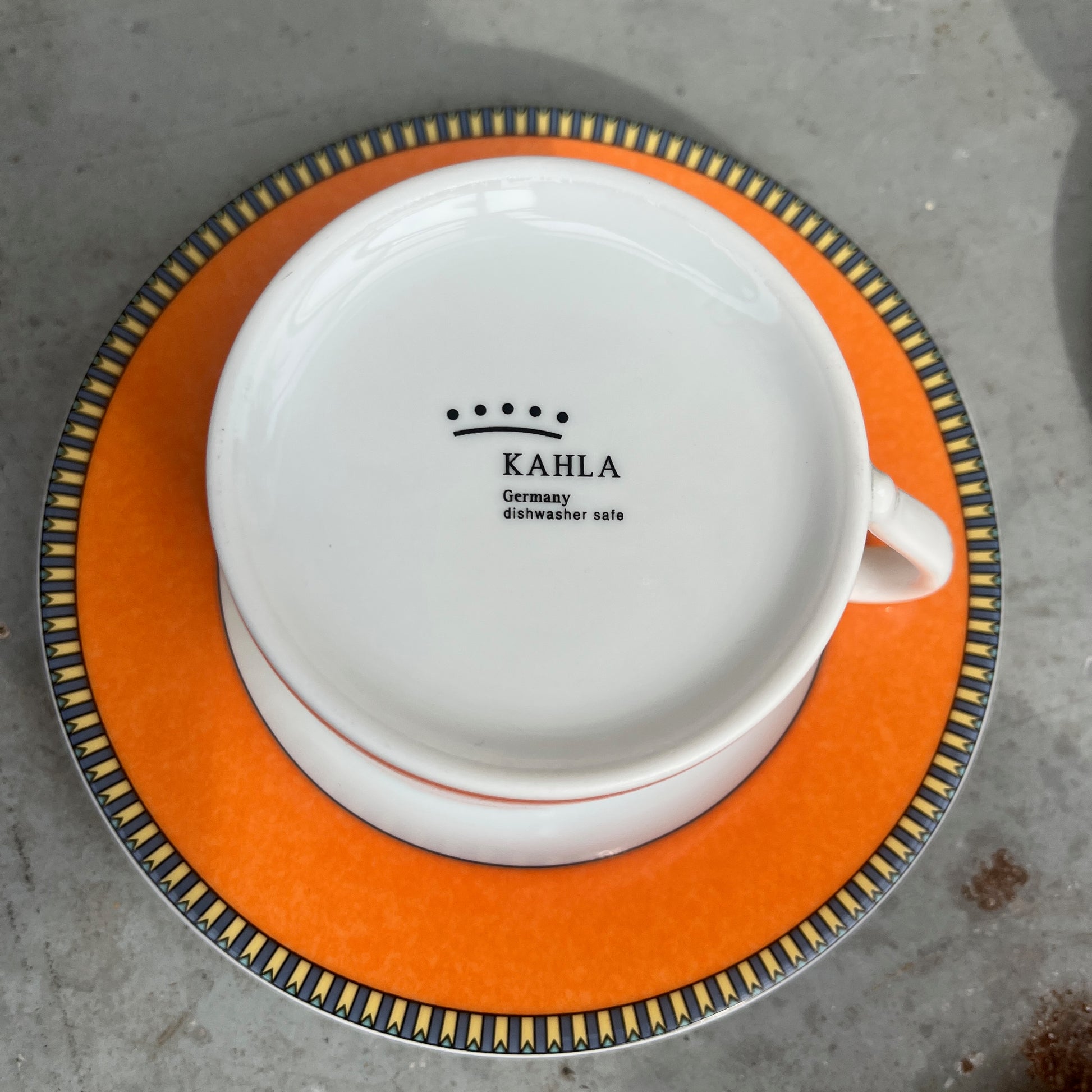 Orange teacups and saucers with decorative rims and white interior.