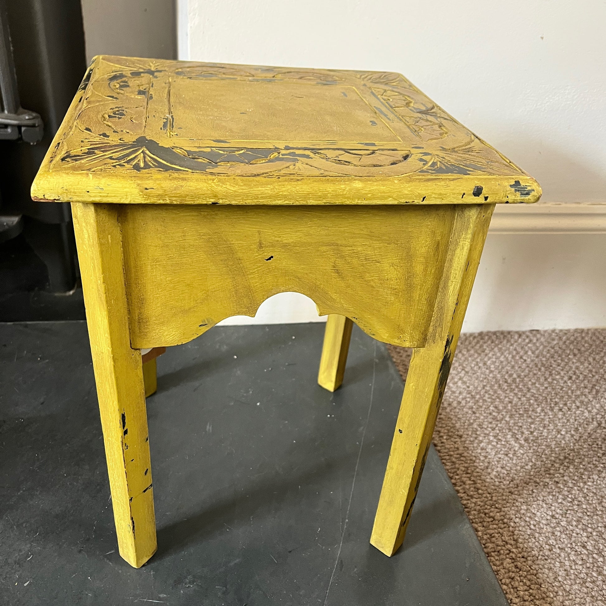 A collection of rustic wooden stools, each with a weathered finish in varying shades of brown, blue and yellow, featuring simple, sturdy designs with four legs