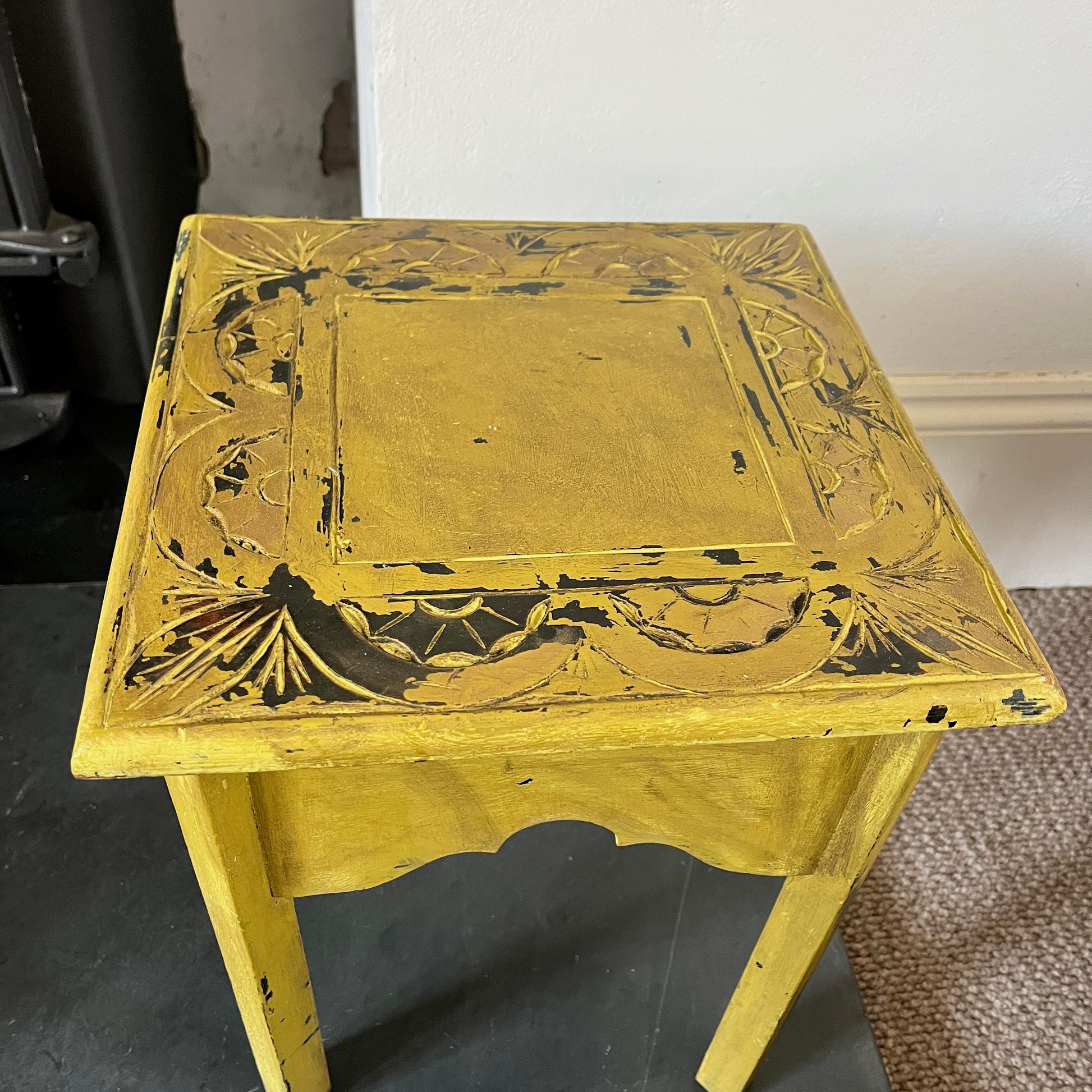 A collection of rustic wooden stools, each with a weathered finish in varying shades of brown, blue and yellow, featuring simple, sturdy designs with four legs