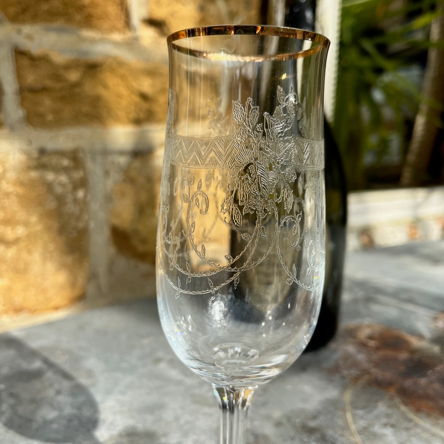 A set of six vintage champagne flutes with elegant gold rims and intricately etched glass, circa mid-20th century. Each flute features delicate floral or geometric etchings on the bowl, complemented by a fine gold band around the rim.