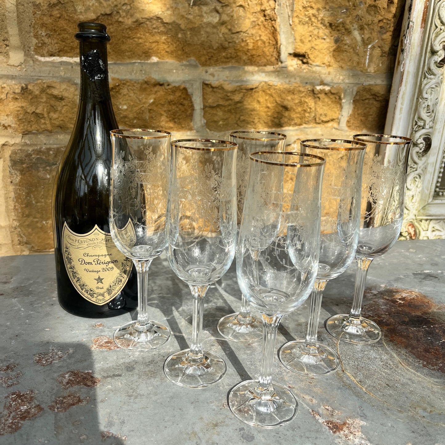 A set of six vintage champagne flutes with elegant gold rims and intricately etched glass, circa mid-20th century. Each flute features delicate floral or geometric etchings on the bowl, complemented by a fine gold band around the rim.