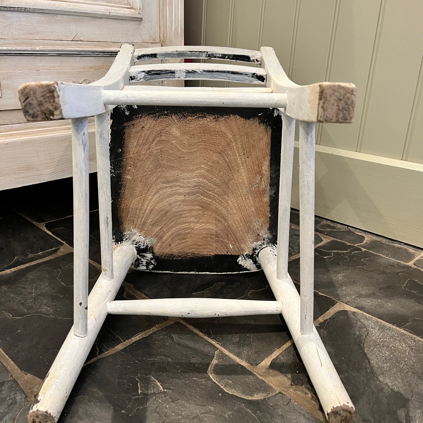 A vintage child's wooden chair with weathered, chippy white paint, showcasing its aged charm
