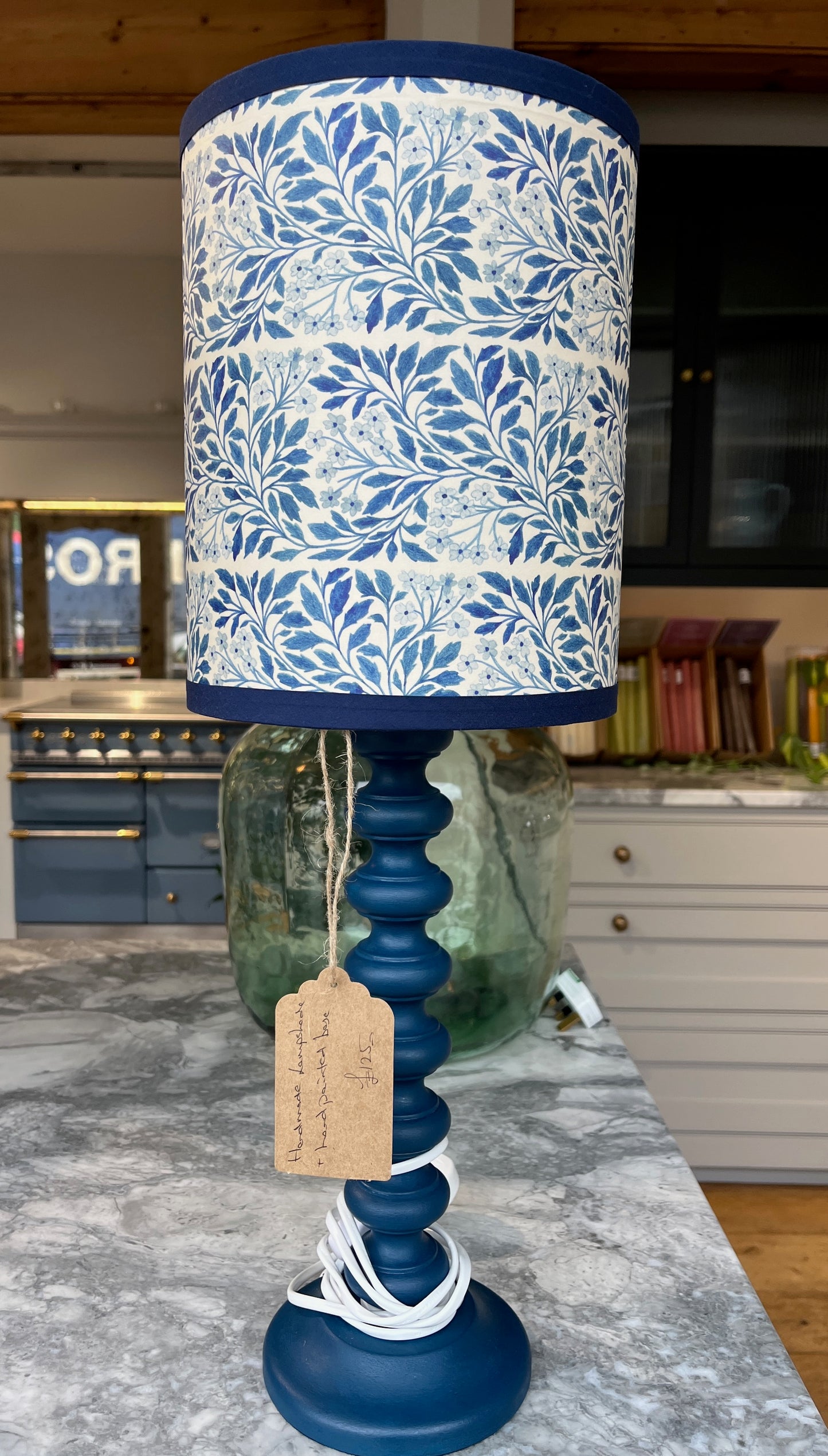 A contemporary handmade lampshade inspired by William Morris, featuring intricate floral and vine motifs in royal blue with royal blue binding around the top and bottom. The shade is complemented with a hand painted bobble base in the same royal blue.