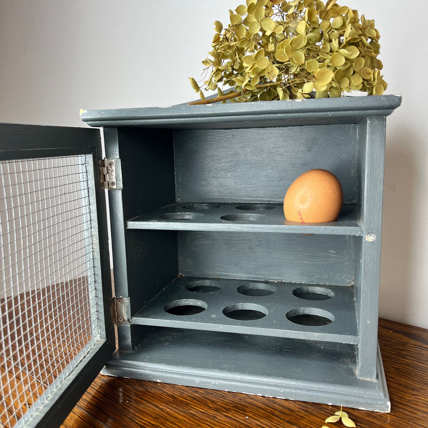 Vintage blue egg cupboard with a rustic, chippy finish