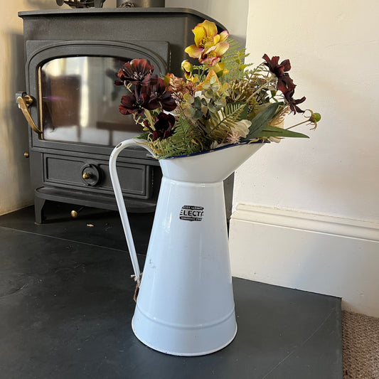 A white enamel jug with a smooth, glossy finish and blue rim (top and bottom). The jug has a classic, slightly curved shape with a sturdy handle