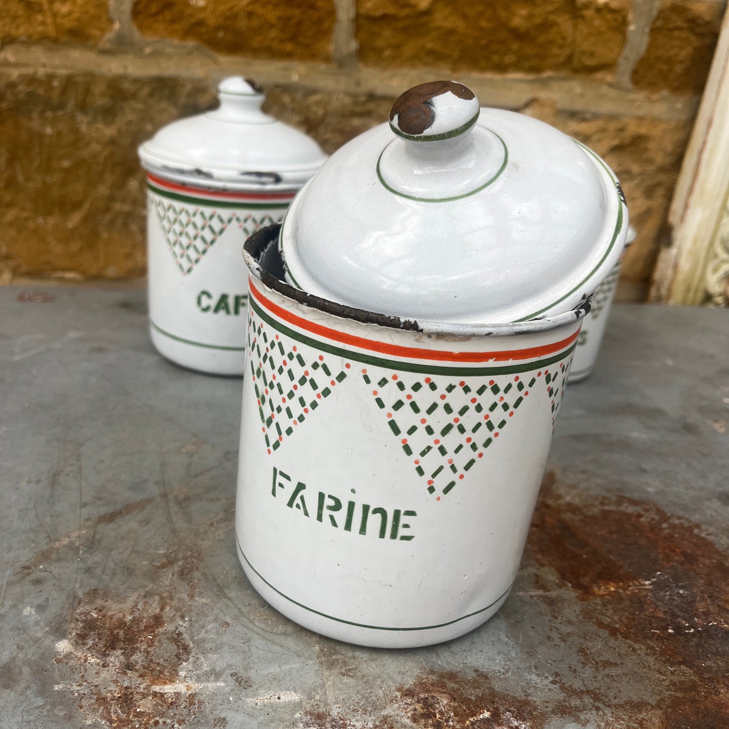 Four vintage white ceramic canisters with lids for flour, coffee, tea, and spices, decorated with green geometric patterns and orange stripes.