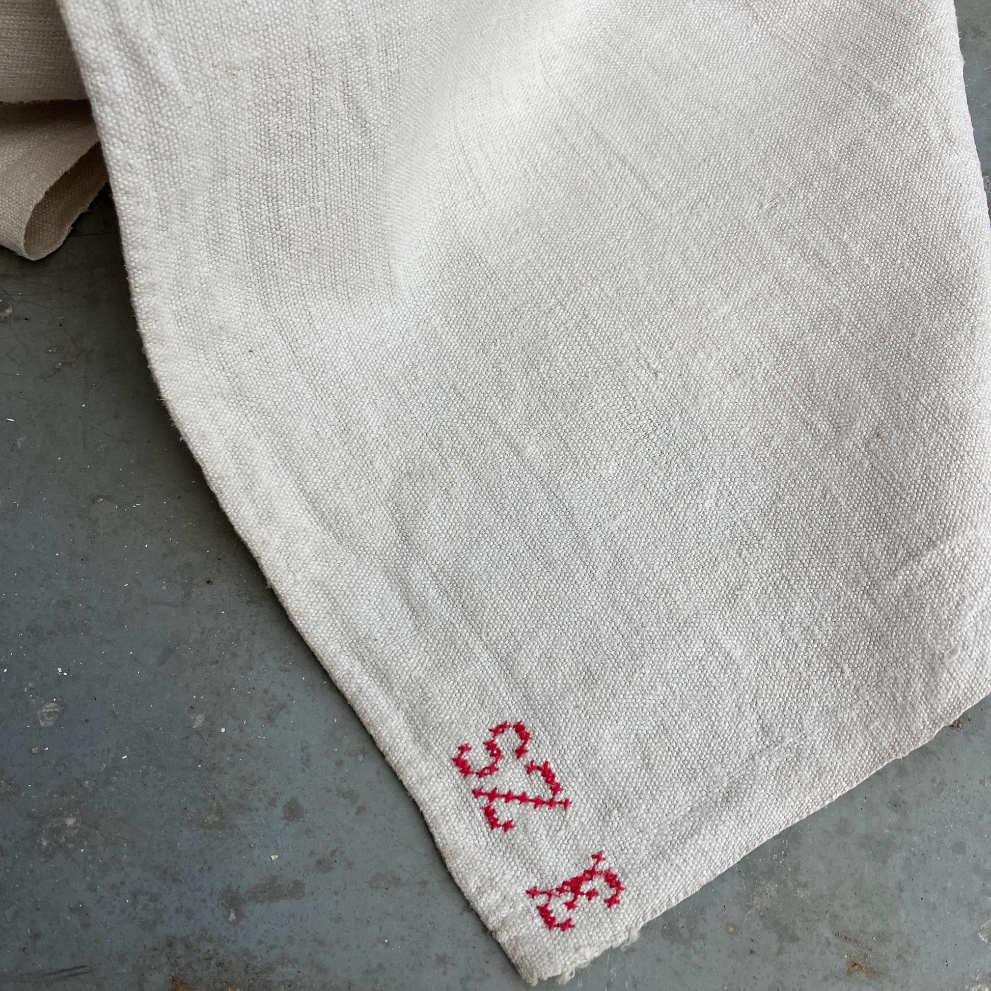 A vintage Hungarian tablecloth featuring white linen and bold red initials, showcasing traditional craftsmanship and a touch of personalized heritage.