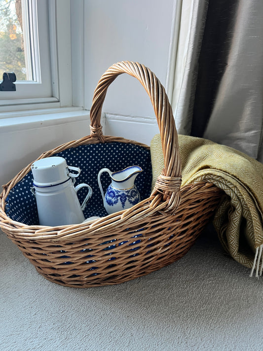 A large wicker basket with a charming blue polka dot fabric lining the interior, adding a playful touch to its rustic exterior